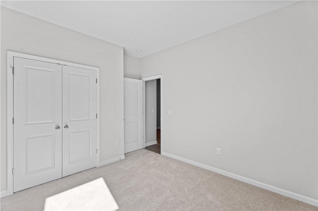Bright bedroom with white double closet doors and adjacent bath entry on beige carpet in Davidson Homes The Luna B, Opelika, AL
