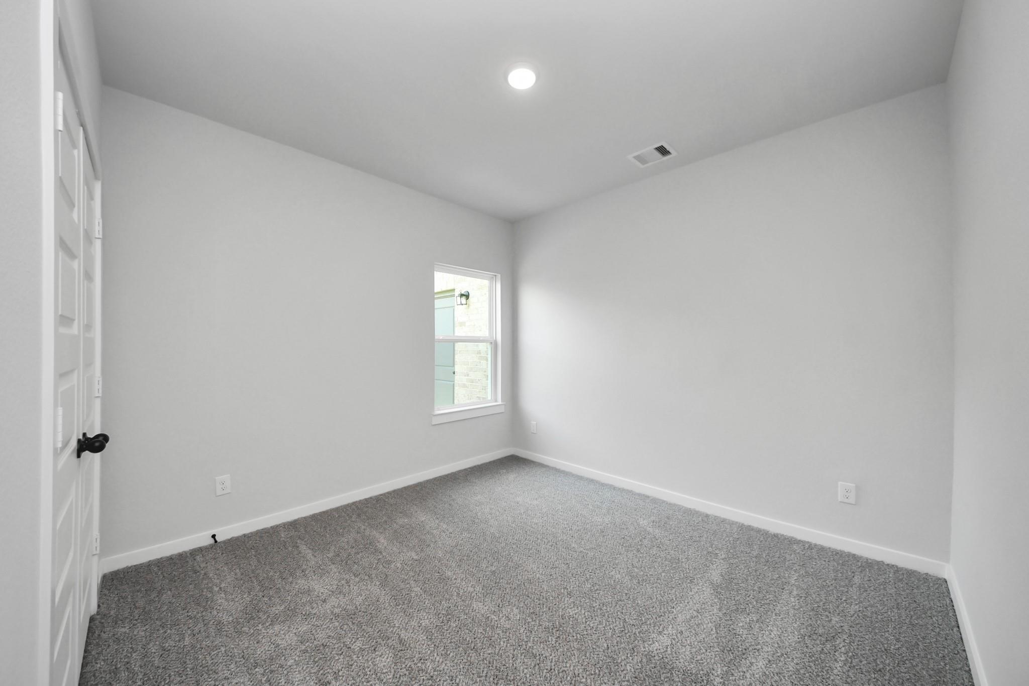 Bright, spacious secondary bedroom with plush carpet in The Riviera C floor plan at River Ranch Meadows, Dayton, Texas.