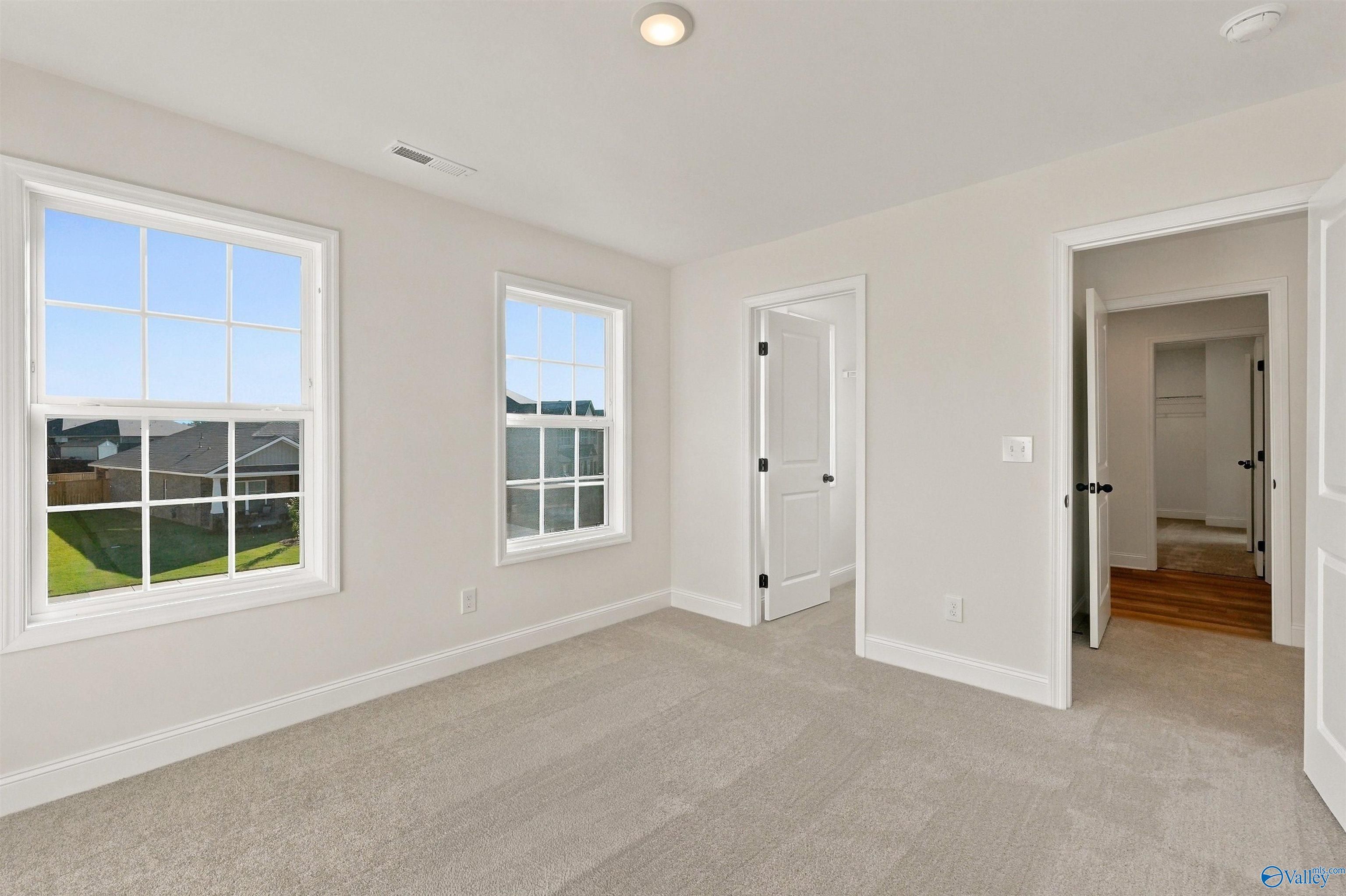 Bright secondary bedroom with plush carpeting and walk-in closet in The Chelsea C floor plan at Creek Grove, New Market.