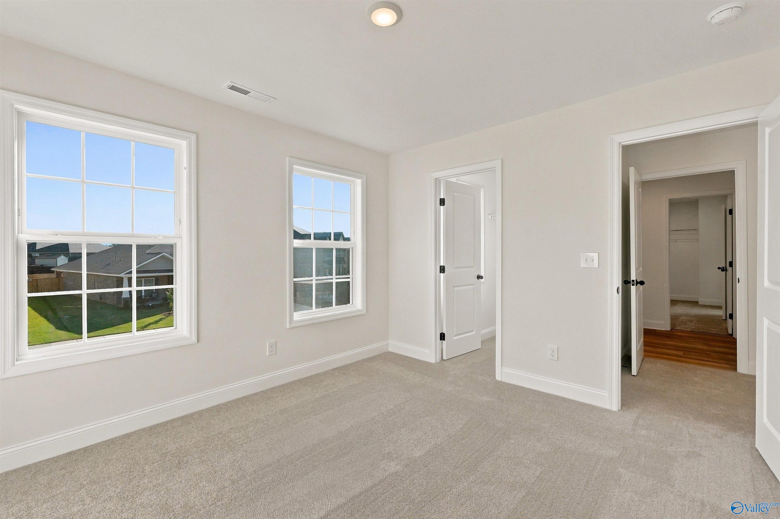 Bright secondary bedroom with plush carpeting and walk-in closet in The Chelsea C floor plan at Creek Grove, New Market.