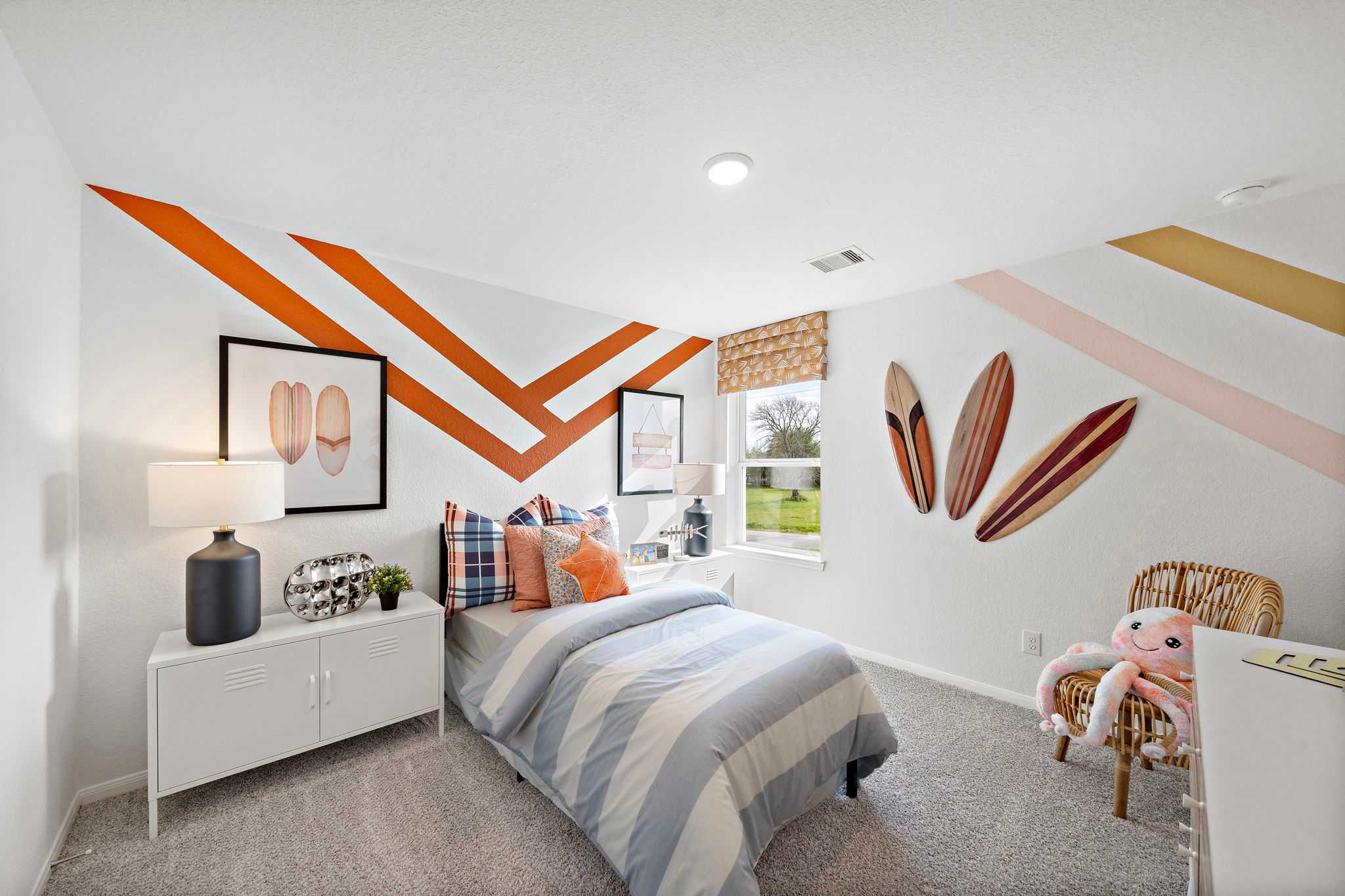 Surf-themed kids bedroom at The Villages at WestPointe in Dayton Texas with orange zigzag walls, twin bed, and surfboard decor