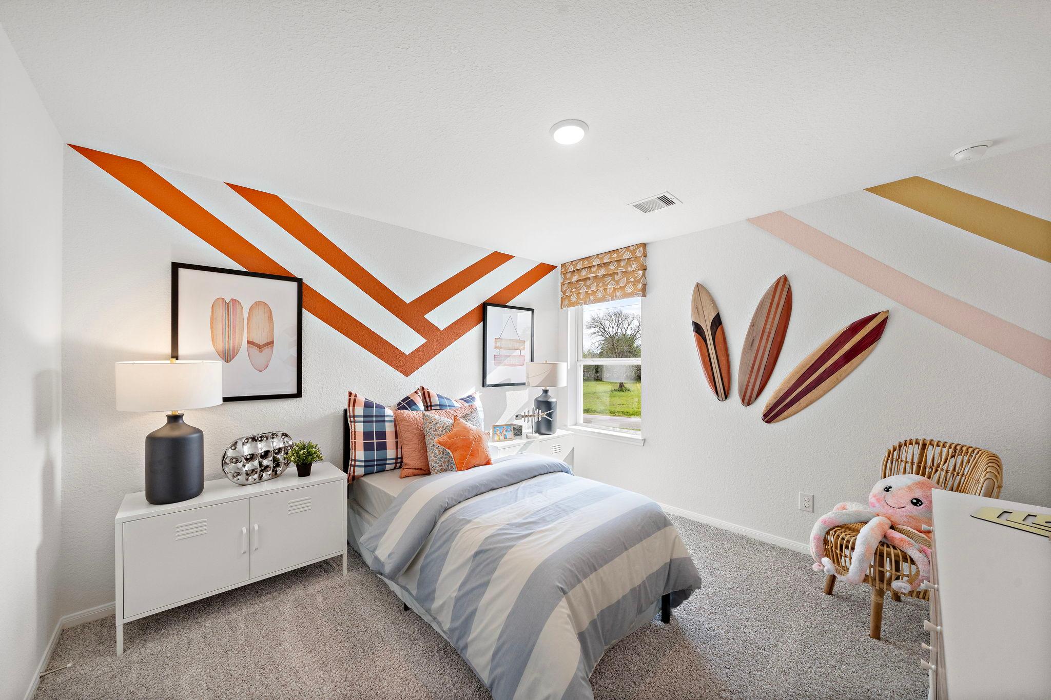 Surf-themed kids bedroom at The Villages at WestPointe in Dayton Texas with orange zigzag walls, twin bed, and surfboard decor