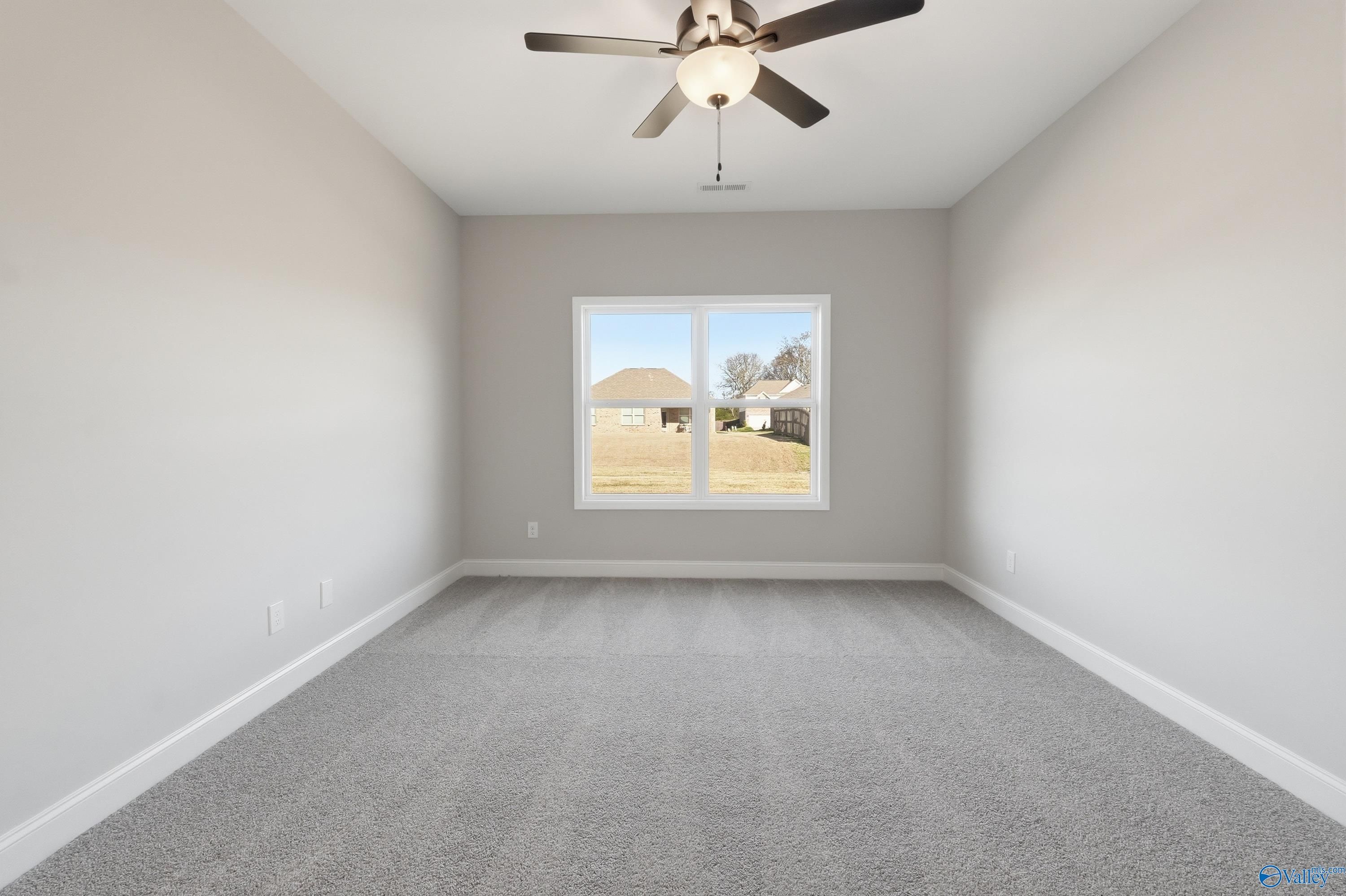 Bright empty bedroom with ceiling fan, large window and neighborhood view in Davidson Homes The Franklin C, New Market, Alabama