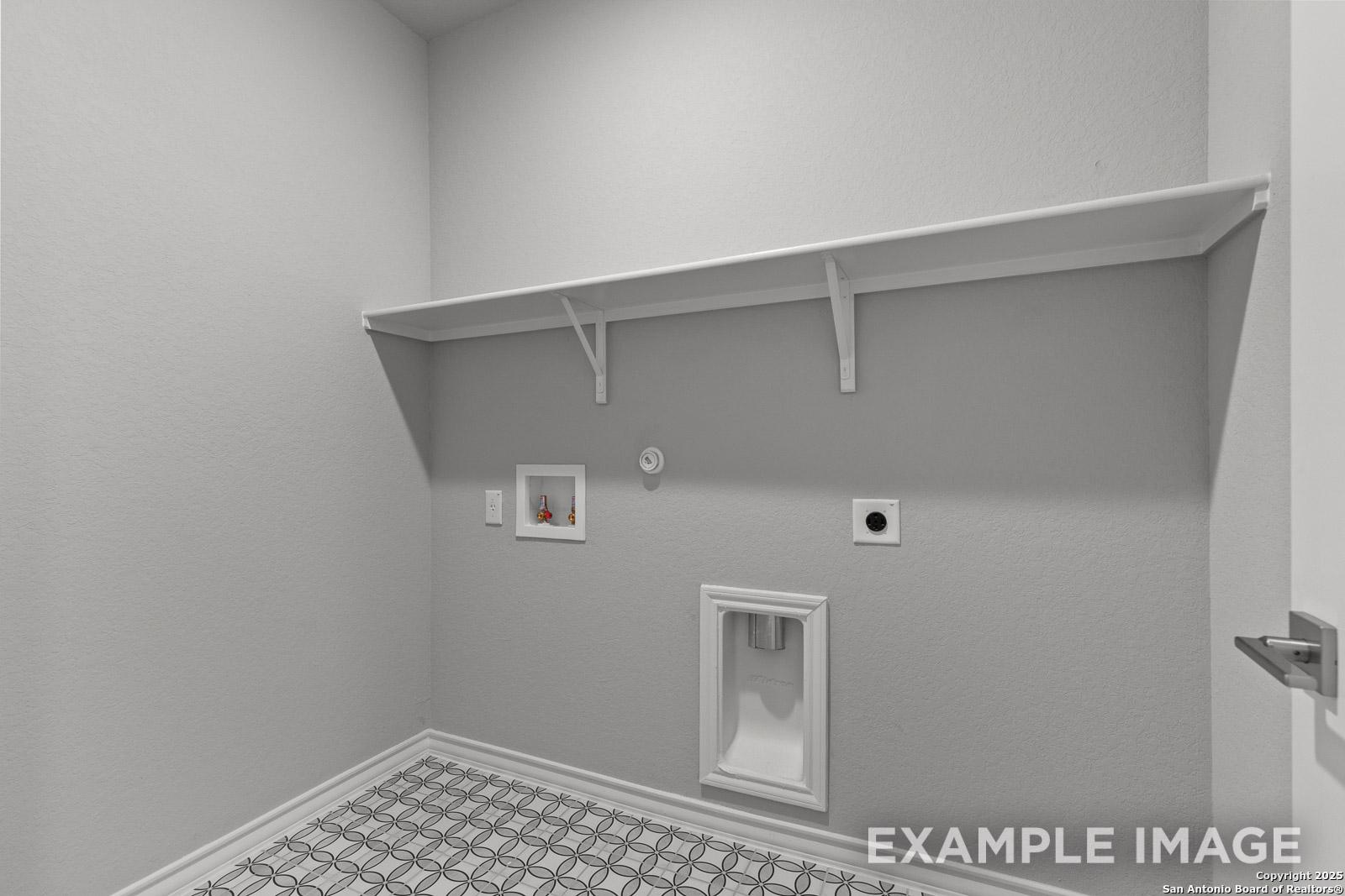 Laundry room in The Oxford home design featuring patterned tile flooring and convenient built-in shelving.