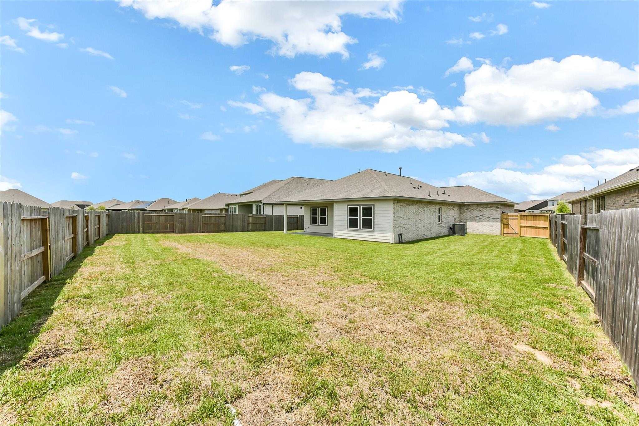 Private fenced backyard with green lawn and wooden privacy fence in Davidson Homes The Laguna C, Sierra Vista, Rosharon, Texas