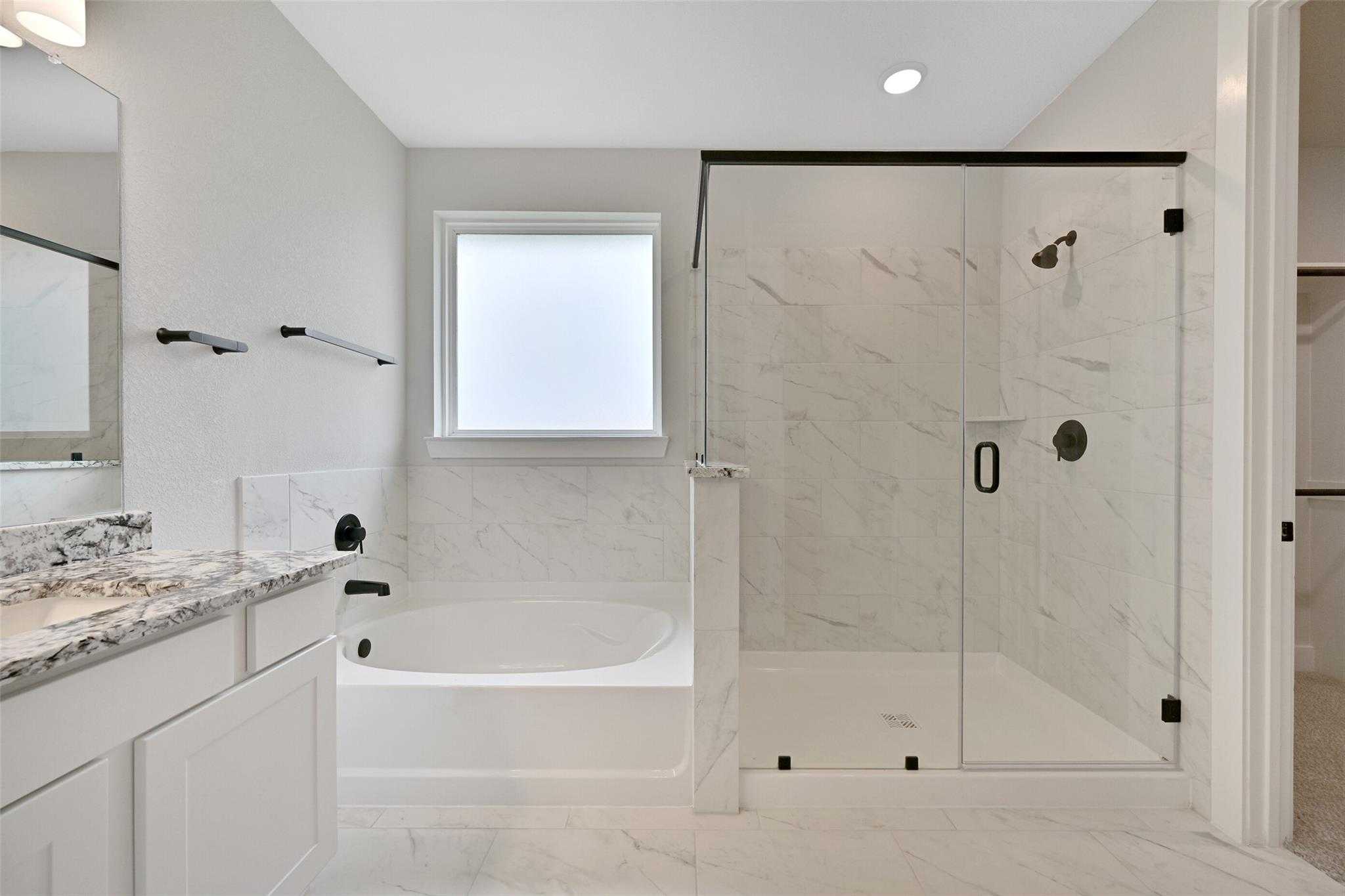 Luxurious master bathroom featuring frameless glass shower, freestanding tub, and quartz double vanity in Davidson Homes The Edward C, Lago Mar, Texas City