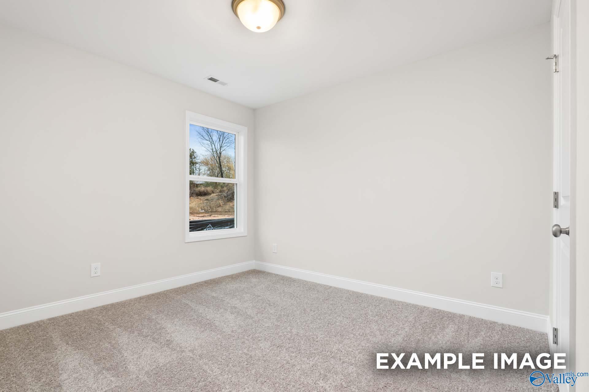 Bright, neutral-toned bedroom with plush carpet in The Asheville E floor plan by Davidson Homes in Forest Glen, Alabama.