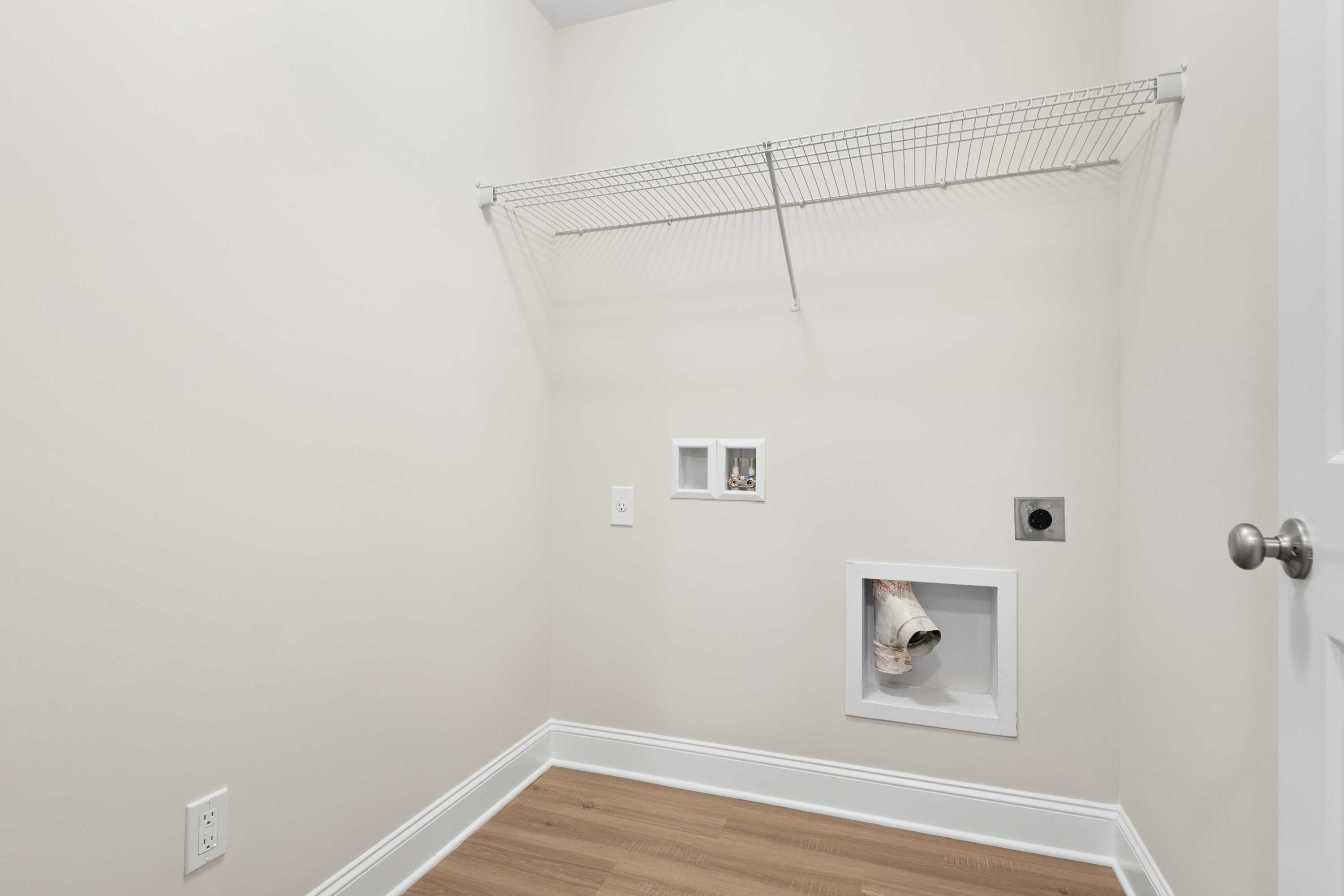 Spacious laundry room in The Asheville home design featuring wire shelving, washer dryer hookups, and neutral walls