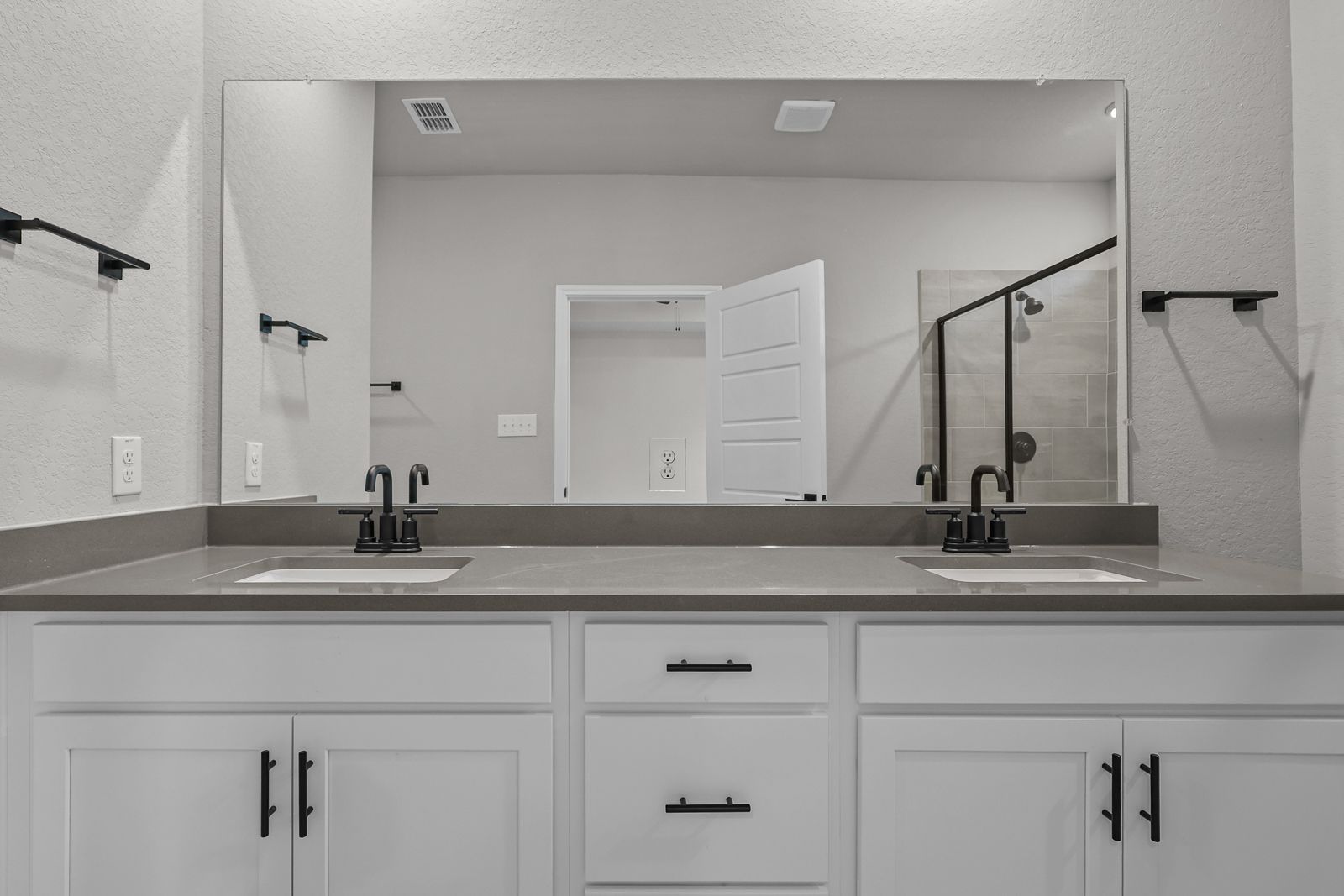 Modern master bathroom in The Glenwood featuring a double vanity with white cabinets, dark hardware, and quartz countertop.