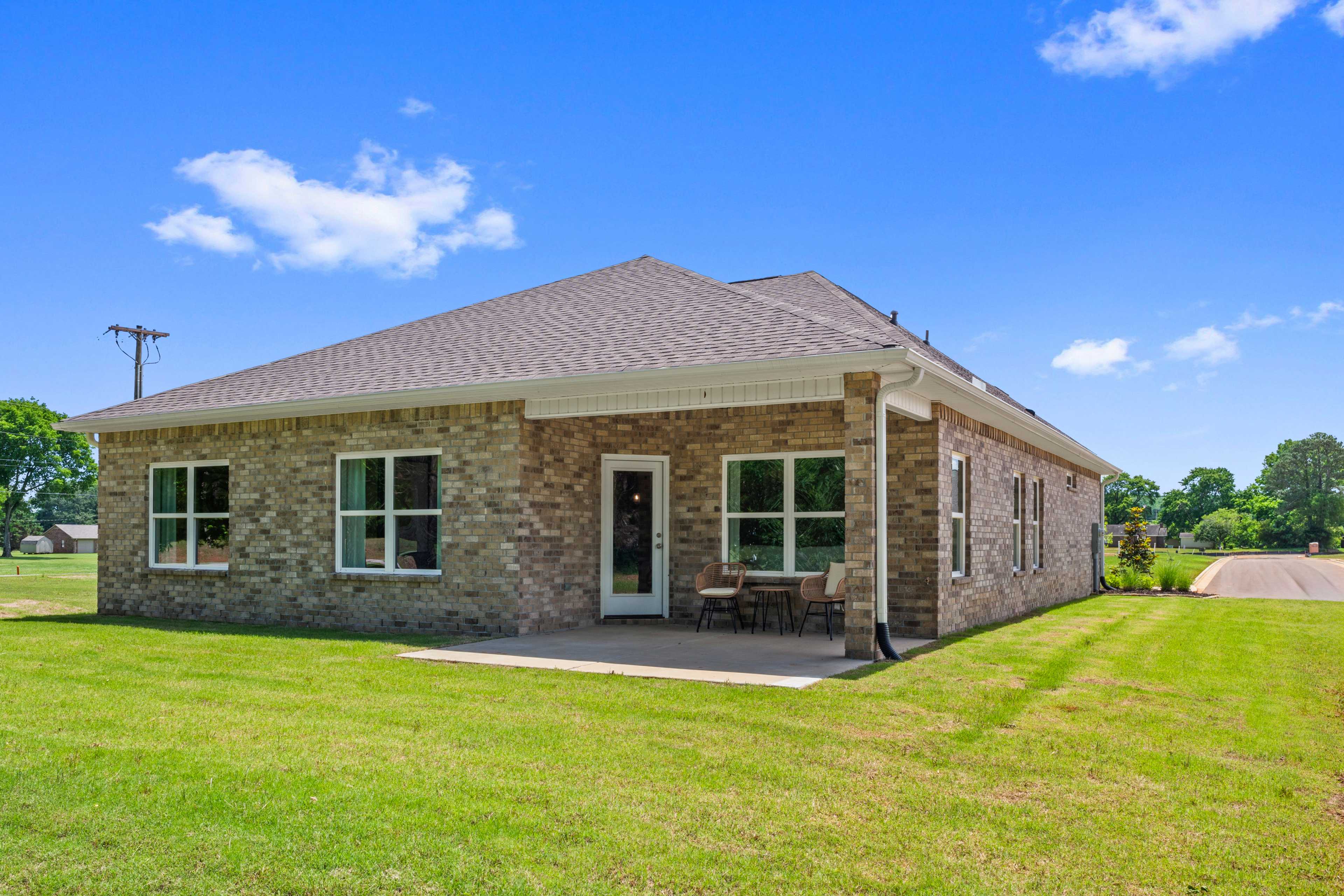 Brick home exterior at Hollon Meadow in Decatur Alabama with covered patio seating and lush green yard