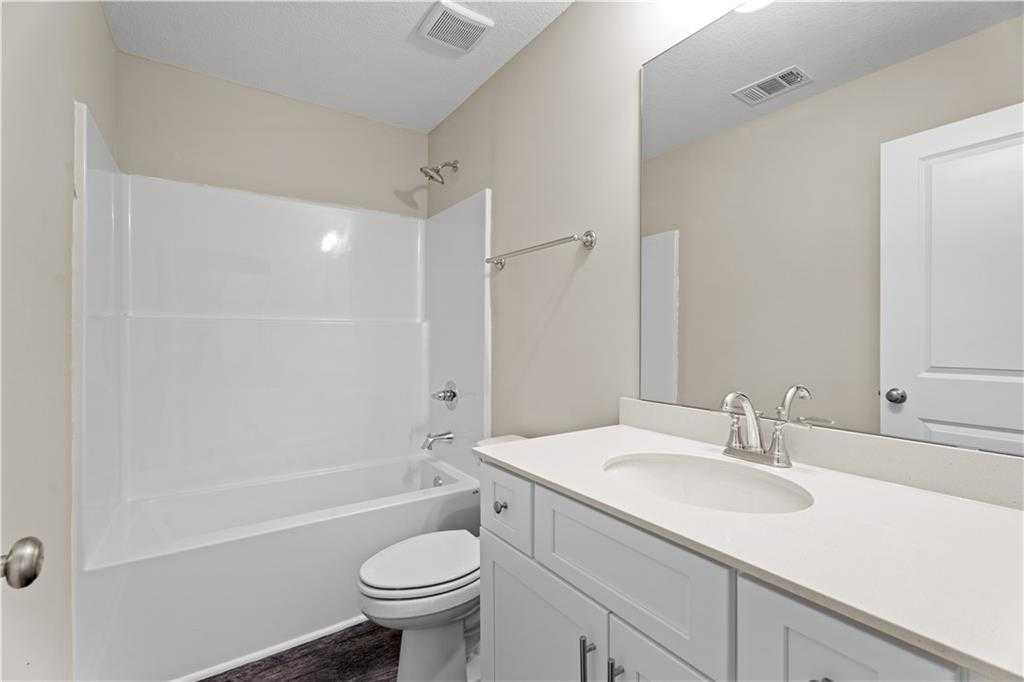 Bright guest bathroom with white subway tile tub/shower, single vanity, and toilet in Davidson Homes The Washington, Phenix City