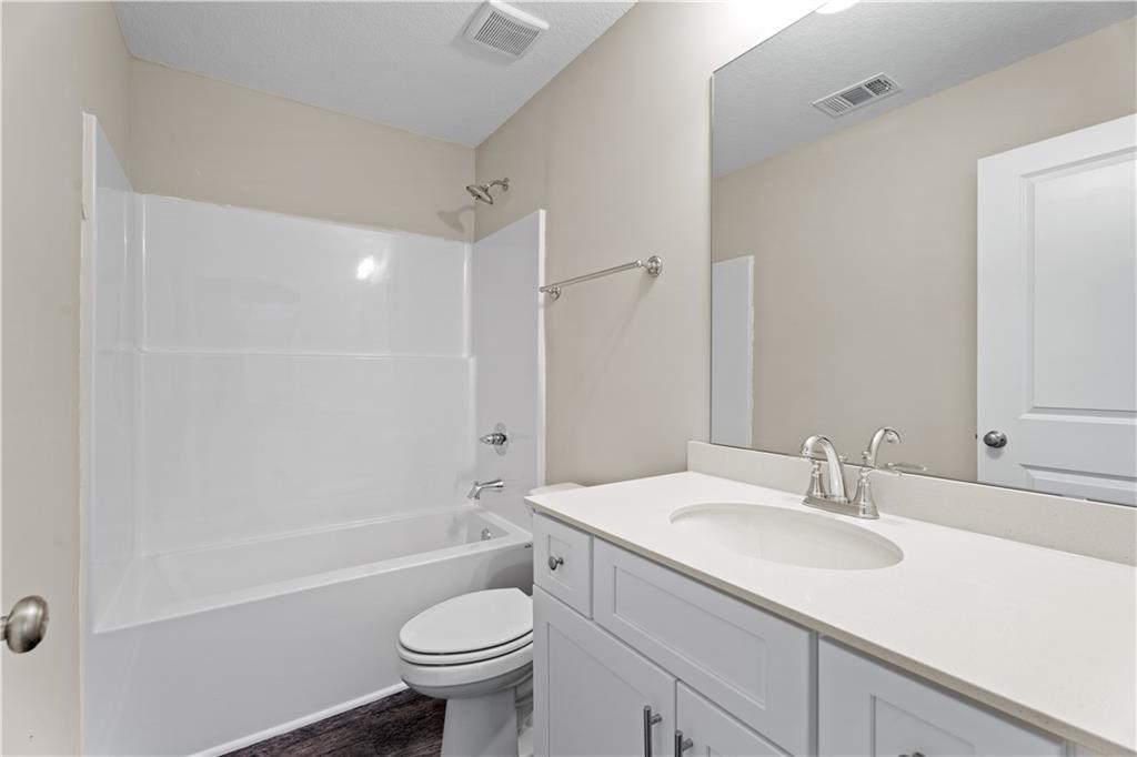 Bright guest bathroom with white subway tile tub/shower, single vanity, and toilet in Davidson Homes The Washington, Phenix City