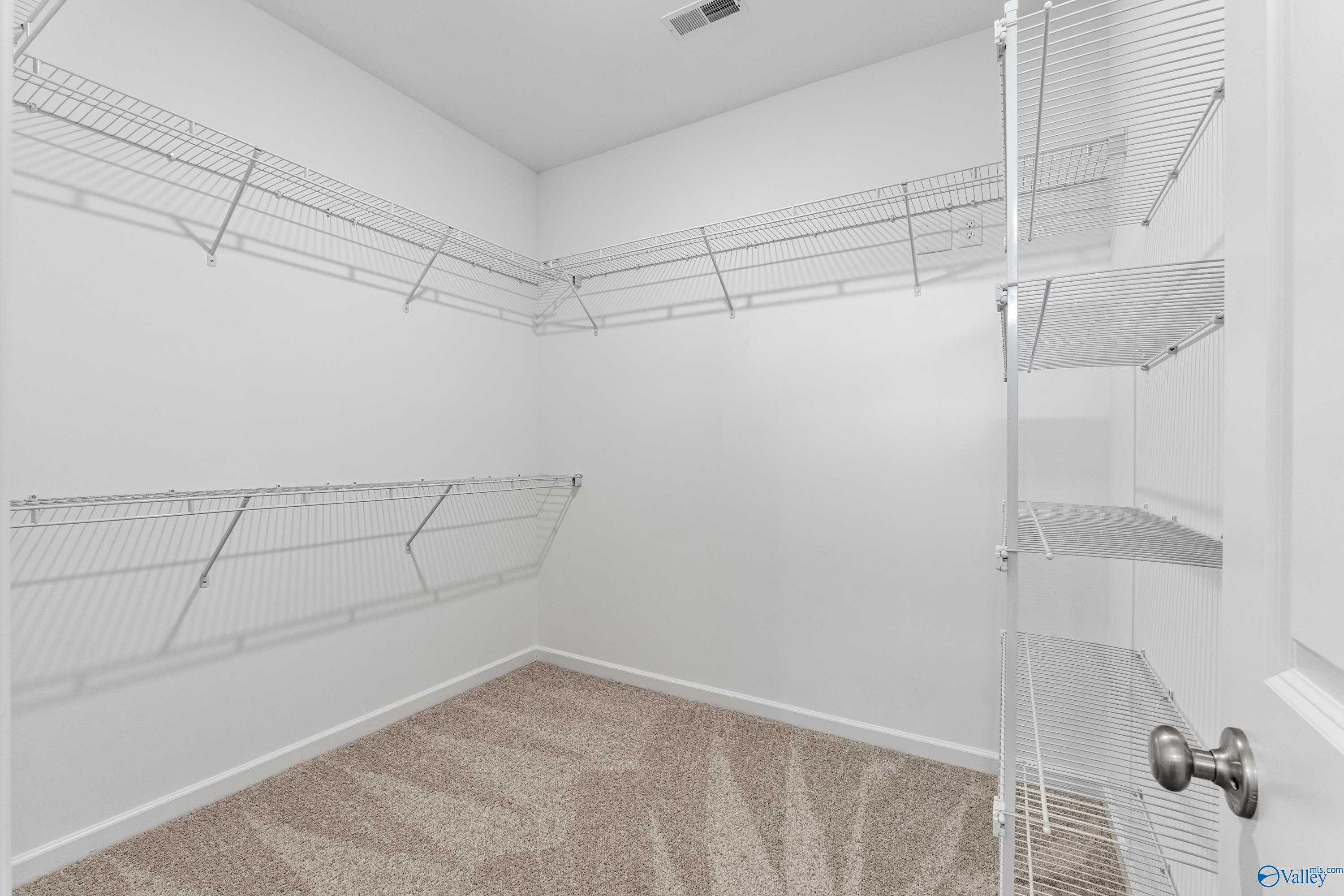 Spacious walk-in closet with white wire shelving and hanging rods in Davidson Homes The Haven, Riverton Preserve, Huntsville, Alabama