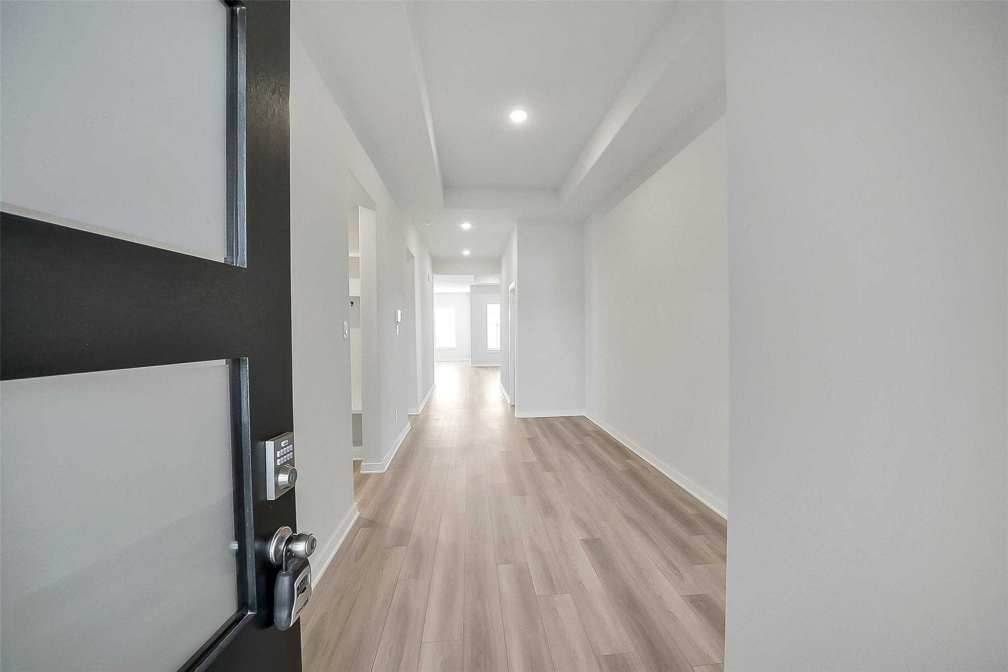 Modern entryway with black front door, frosted glass panel, and light oak floors in Davidson Homes The Acadia A, Katy, Texas