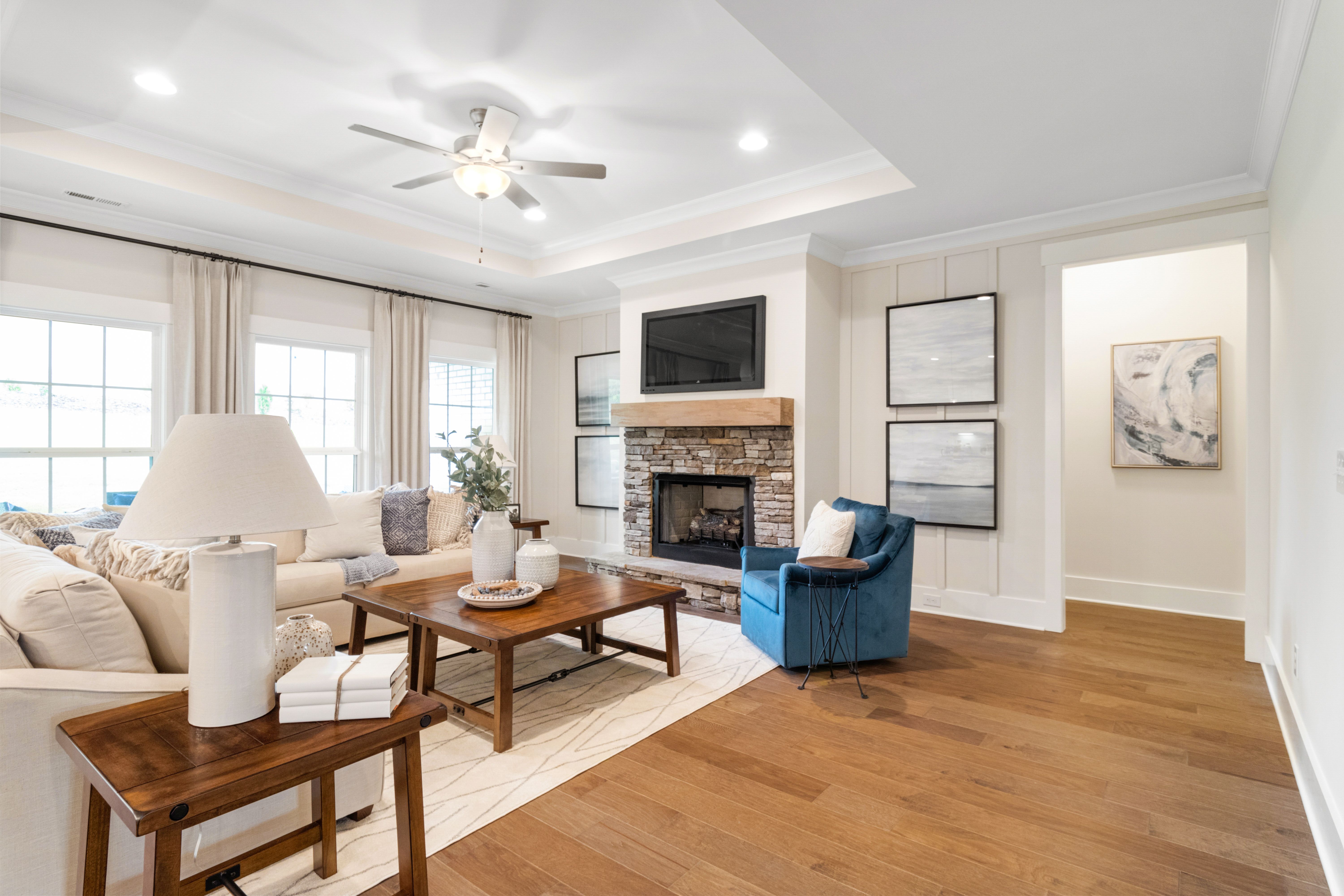 Cozy open-concept living room at Noble Ridge in Cullman Alabama with stone fireplace, hardwood floors, and neutral decor