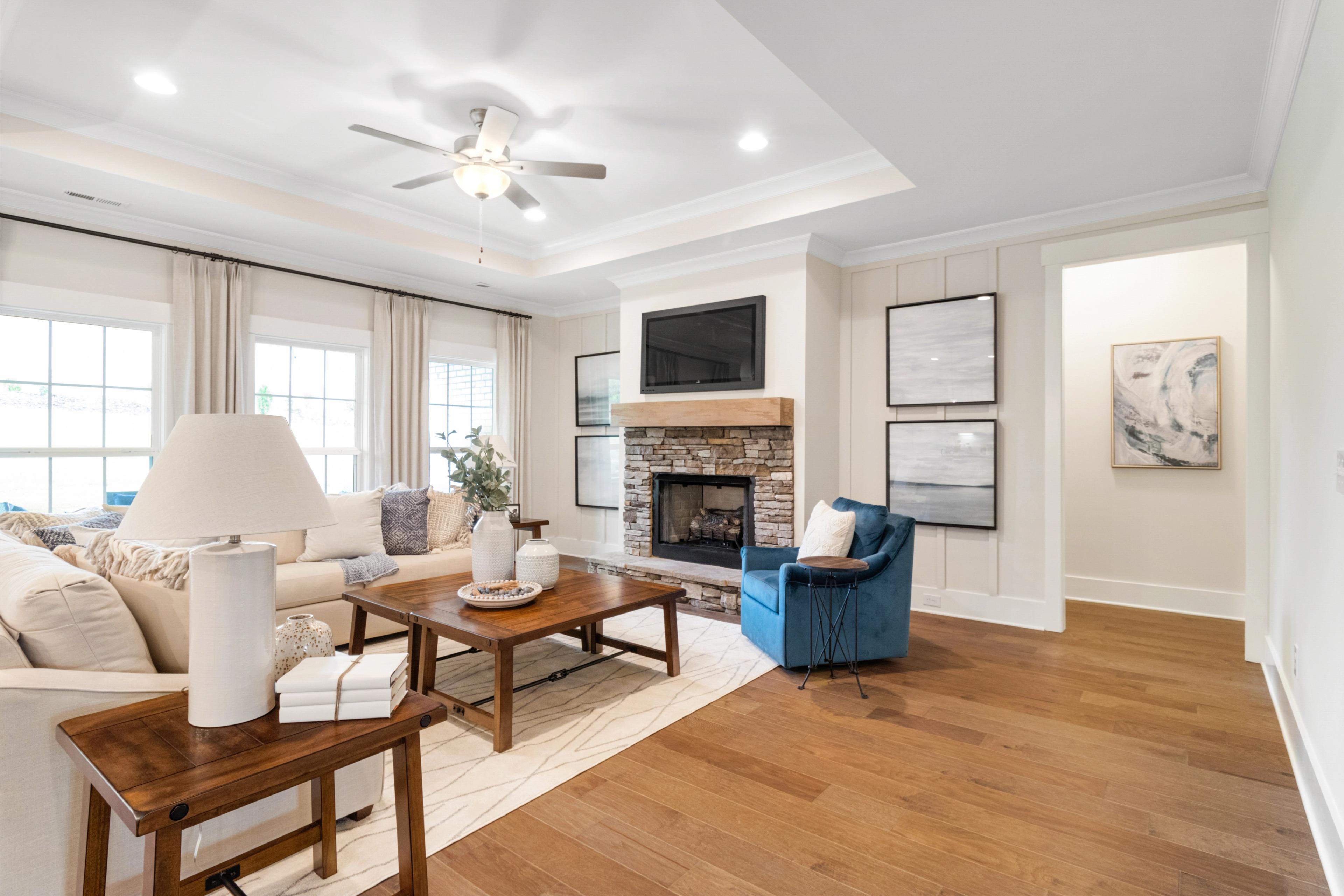 Cozy open-concept living room at Noble Ridge in Cullman Alabama with stone fireplace, hardwood floors, and neutral decor