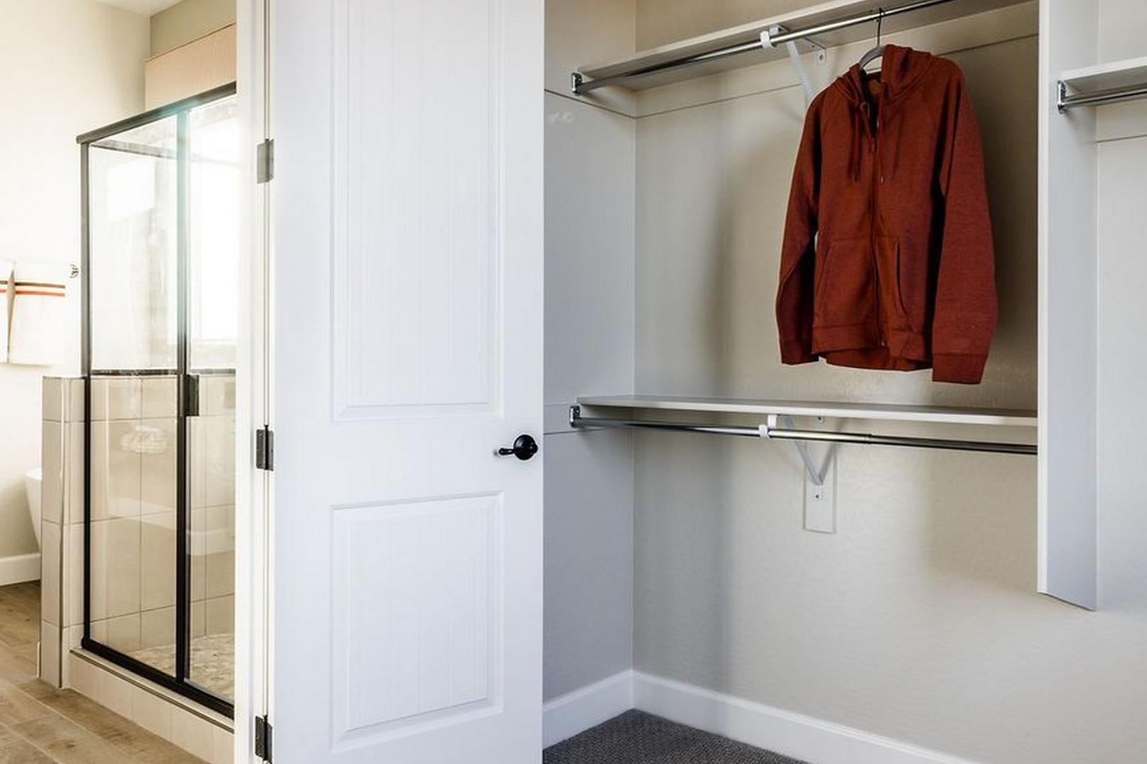 Master bathroom with frameless glass shower and walk-in closet featuring built-in shelving in The Monarch B home