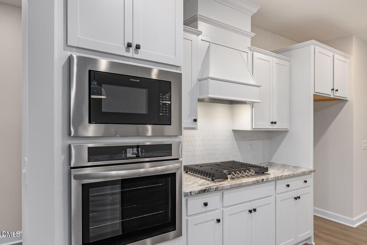 Modern kitchen with white shaker cabinets, stainless Frigidaire double oven, gas cooktop, quartz counters in Davidson Homes The Mitchell, Knightdale NC