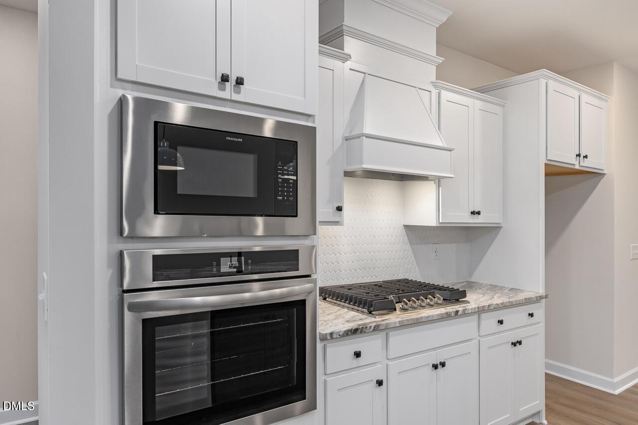Modern kitchen with white shaker cabinets, stainless Frigidaire double oven, gas cooktop, quartz counters in Davidson Homes The Mitchell, Knightdale NC