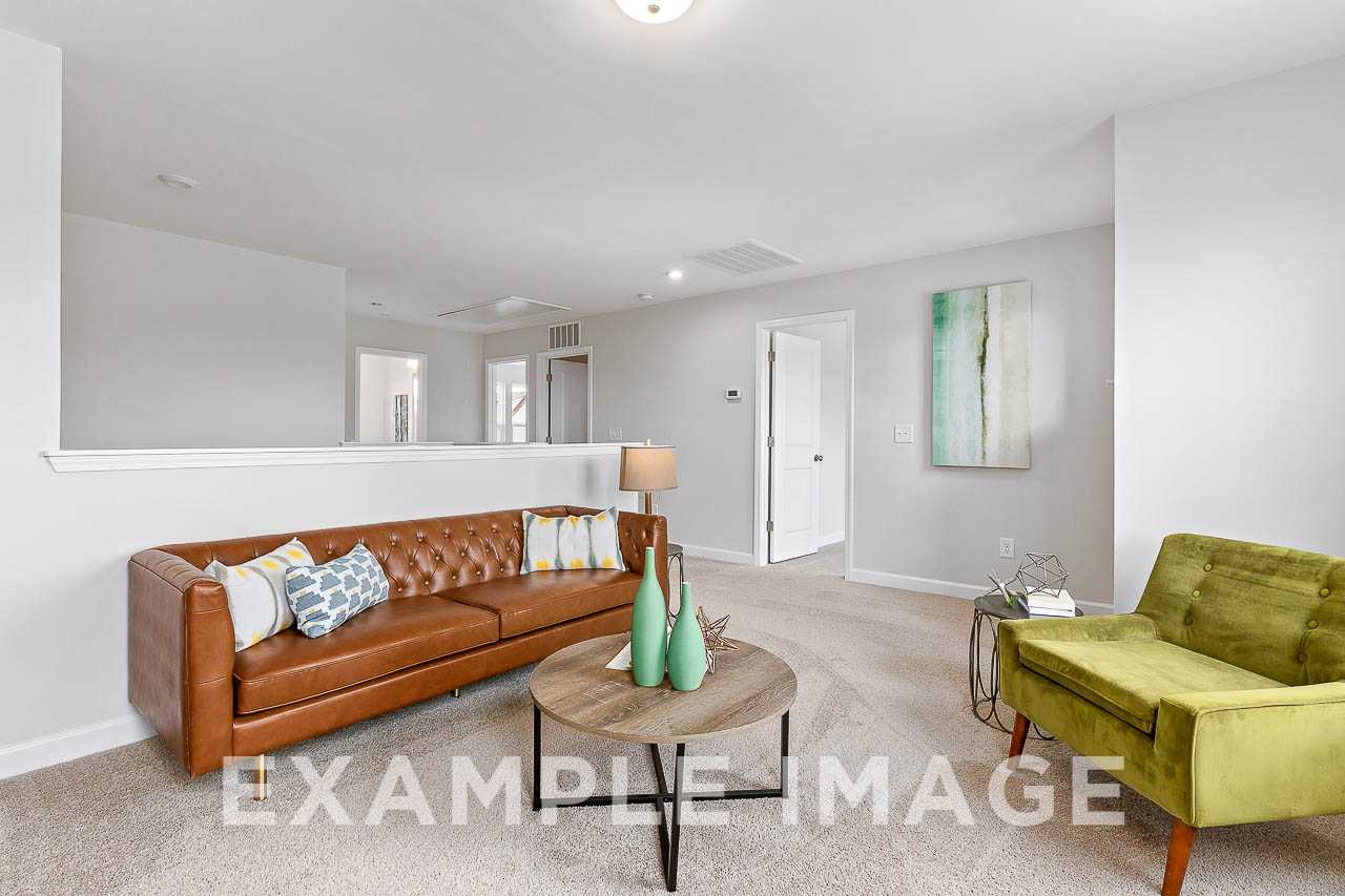 Cozy upstairs loft in The Willow C home design with brown leather sofa, green velvet chair, and wooden coffee table