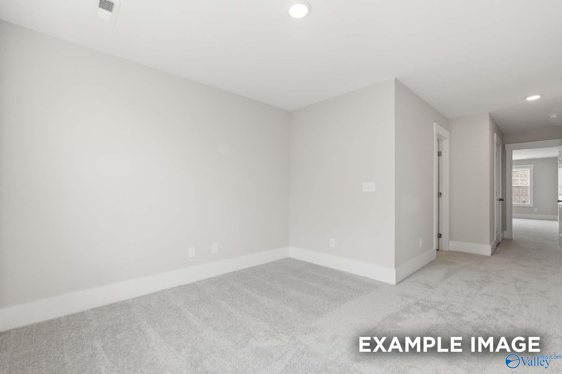 Spacious, neutral-toned bedroom with plush carpet in The Harrison floor plan by Davidson Homes in Meridianville, Alabama.