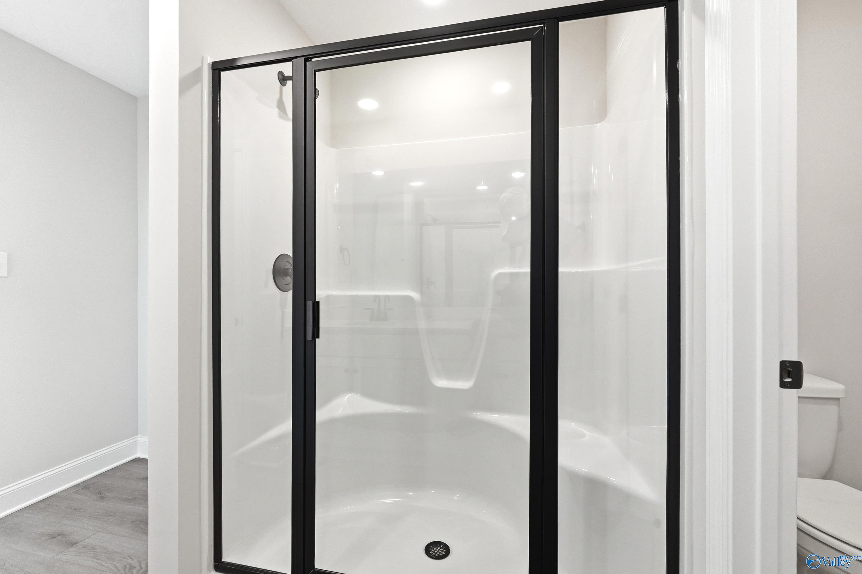 Modern walk-in shower with black frame in The Burton B floor plan at Heritage Lakes, New Market, Alabama.