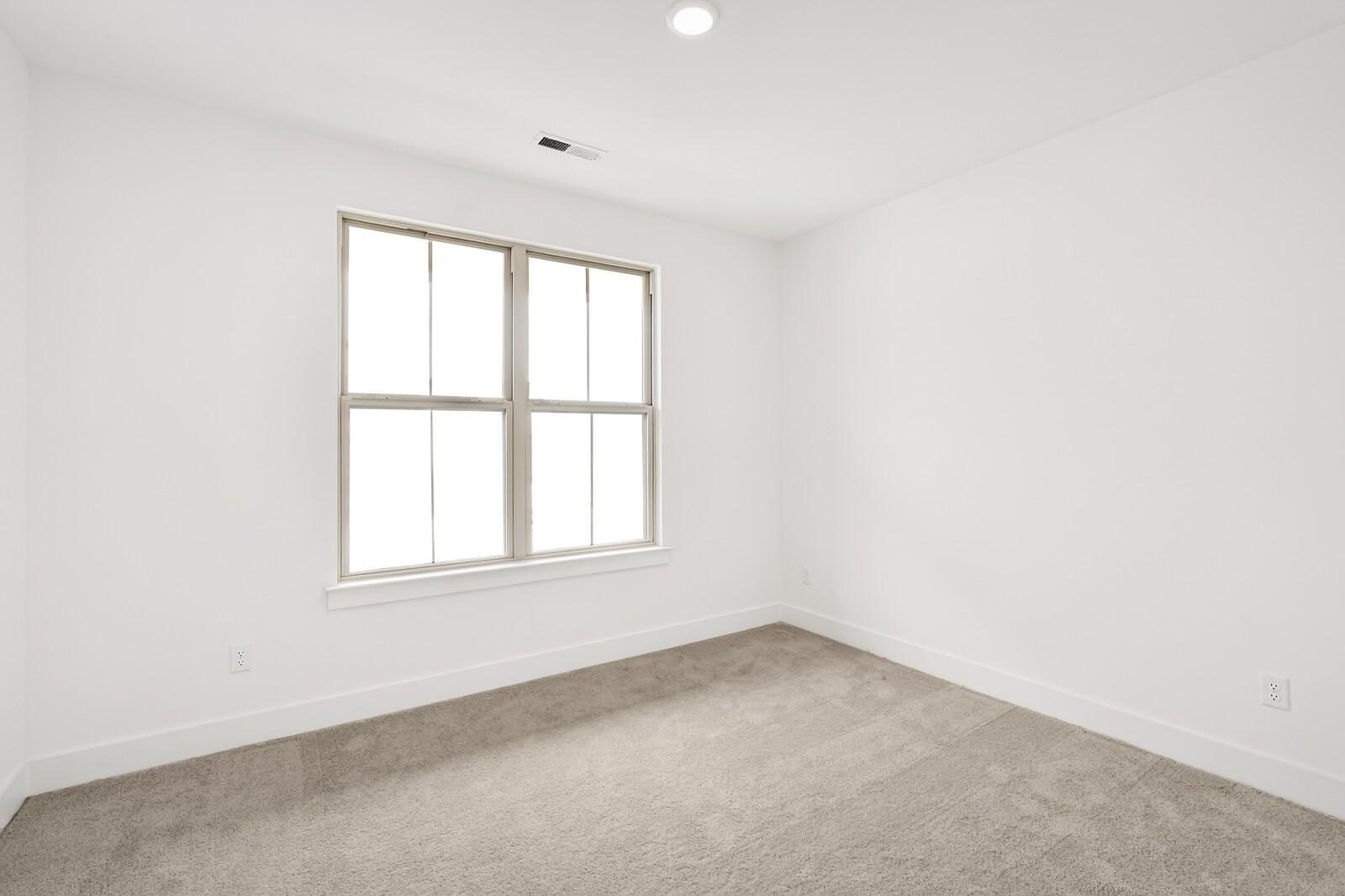 Bright empty bedroom with large window, white walls, and beige carpet in Davidson Homes Ridgeport C, Gallatin, TN