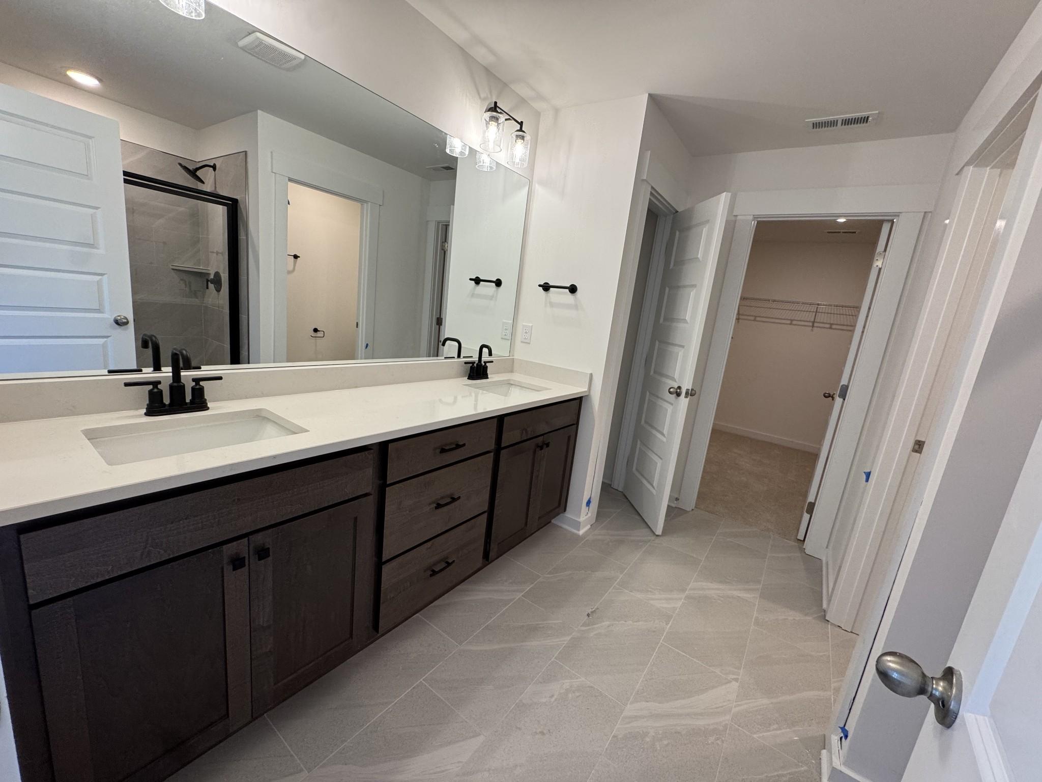 Modern master bathroom featuring double vanity with dark cabinets, white quartz counters, walk-in shower in Davidson Homes The Logan C, Gallatin, Tennessee