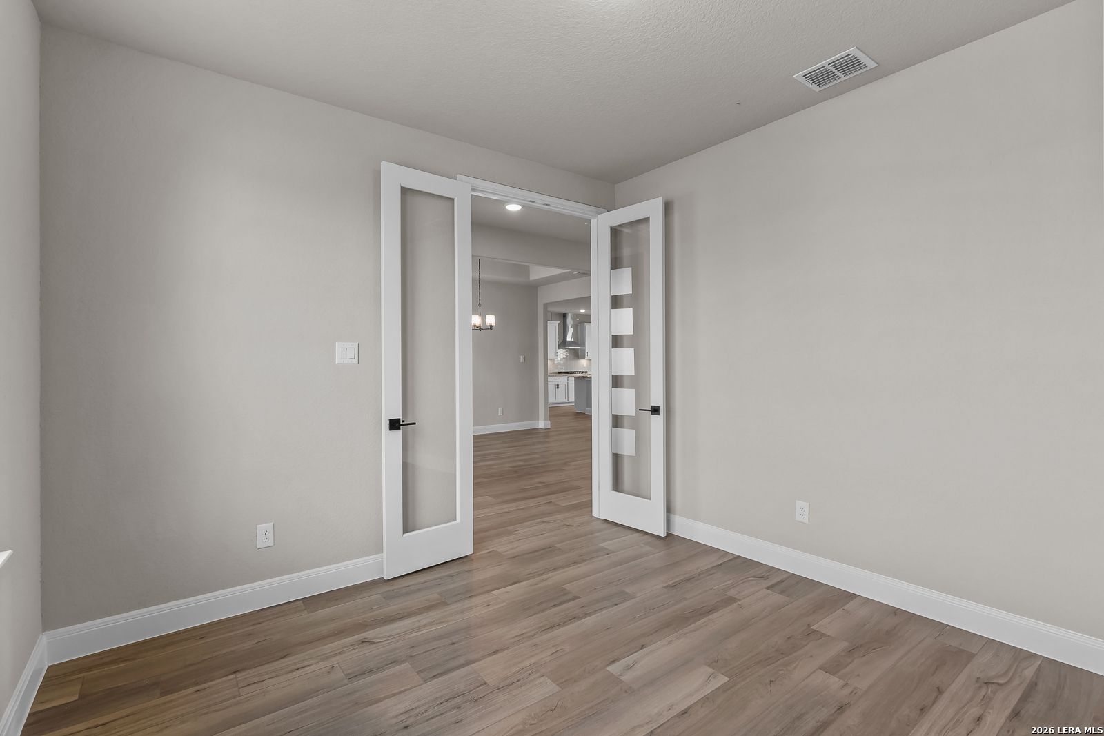 Flexible bedroom with glass-panel French doors and wood-look flooring in Davidson Homes The Foster E, Potranco Oaks, Castroville