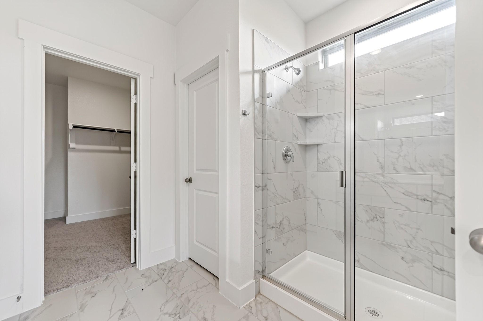 Marble-tiled walk-in shower with glass door in Davidson Homes The Holly F bathroom in Meadow Ridge Estates, Josephine, Texas