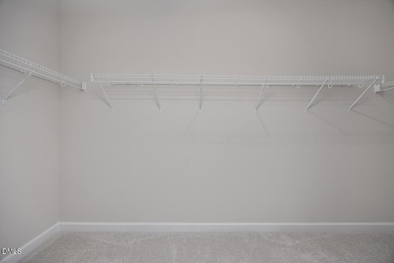 Spacious walk-in closet with white wire shelving along beige walls in The Daphne C master suite, Lillington, NC