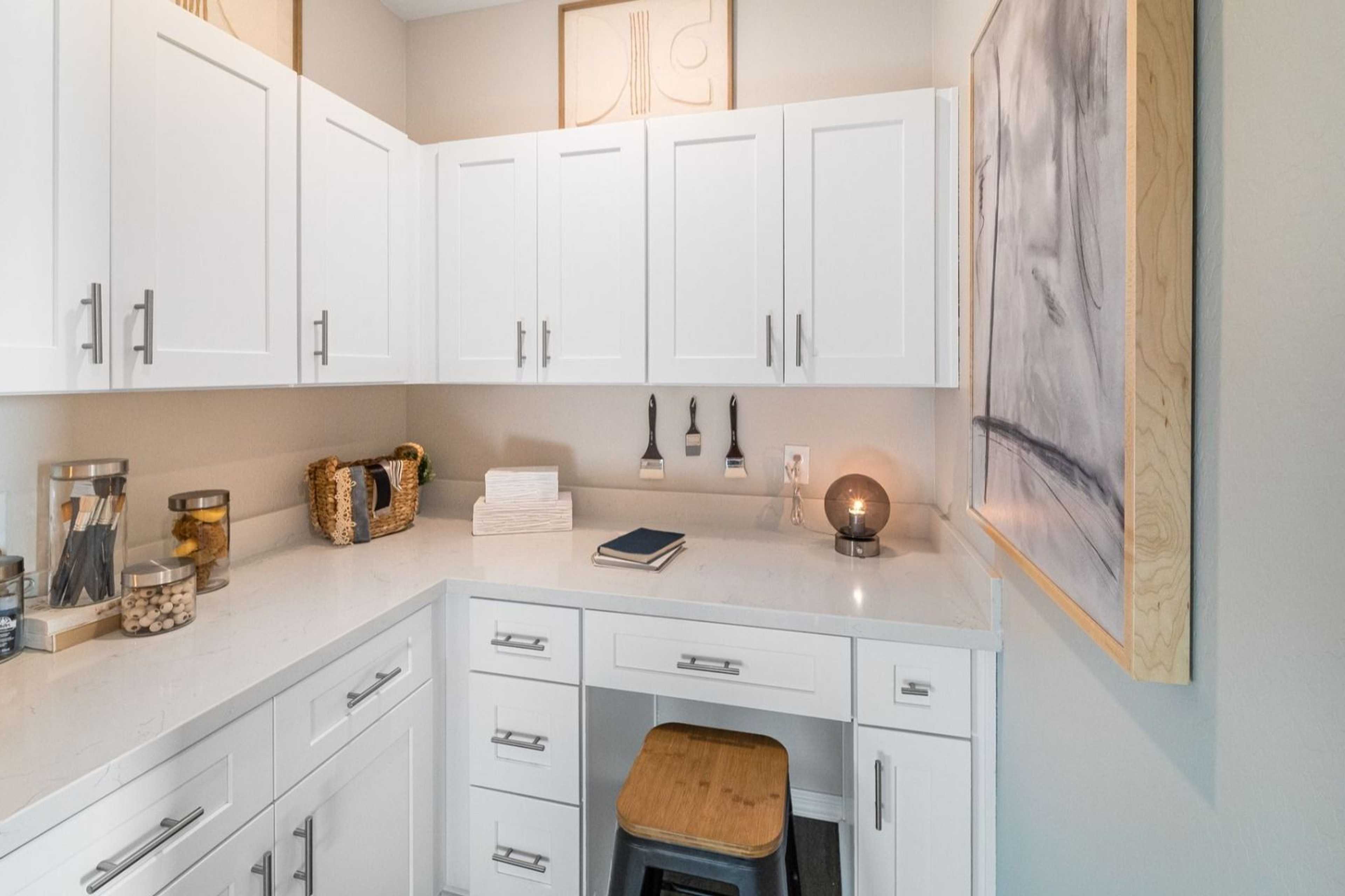 Compact white cabinetry corner desk in South Ranch Destination Collection, Prescott AZ with quartz countertop, wooden stool and organized storage