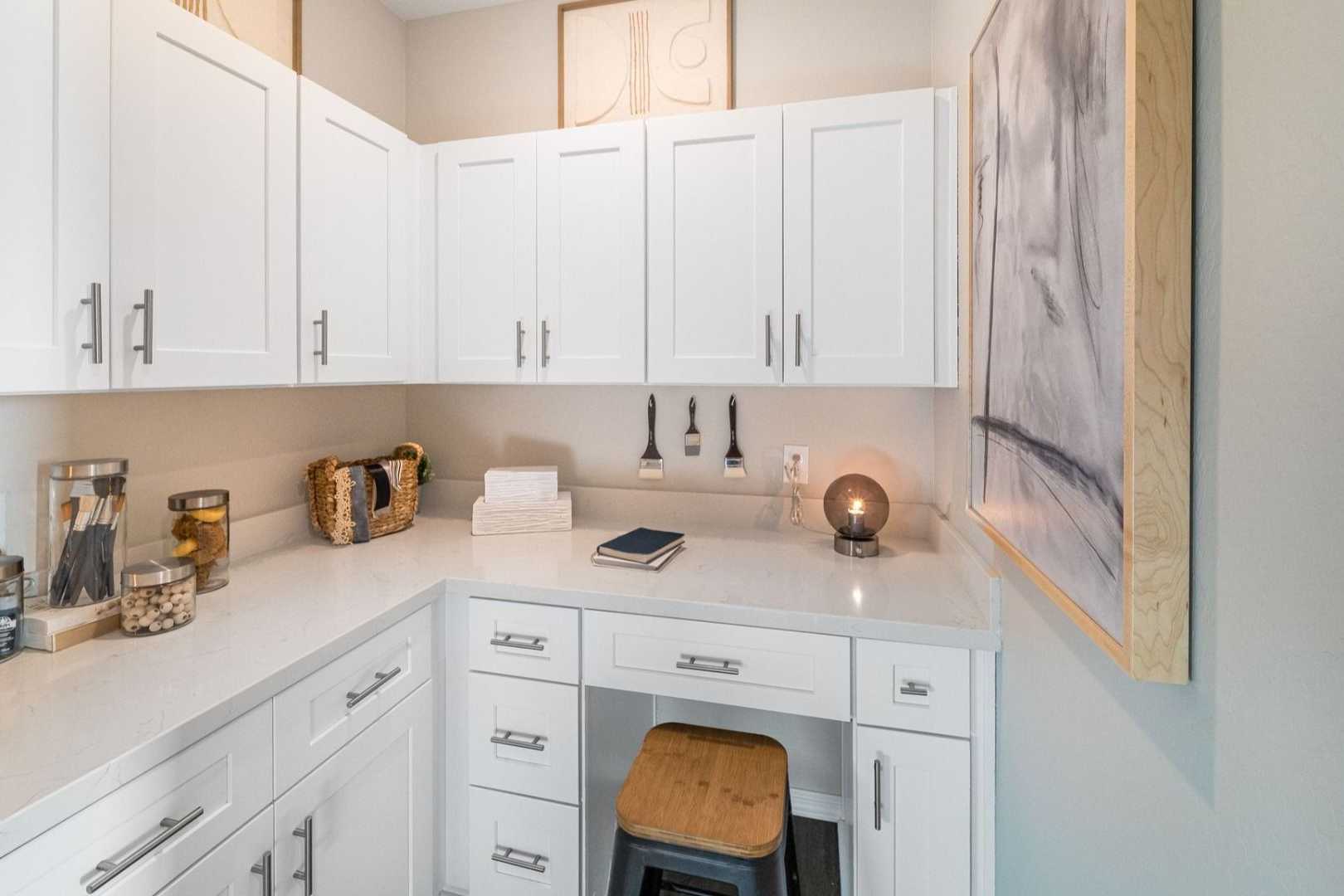 Compact white cabinetry corner desk in South Ranch Destination Collection, Prescott AZ with quartz countertop, wooden stool and organized storage