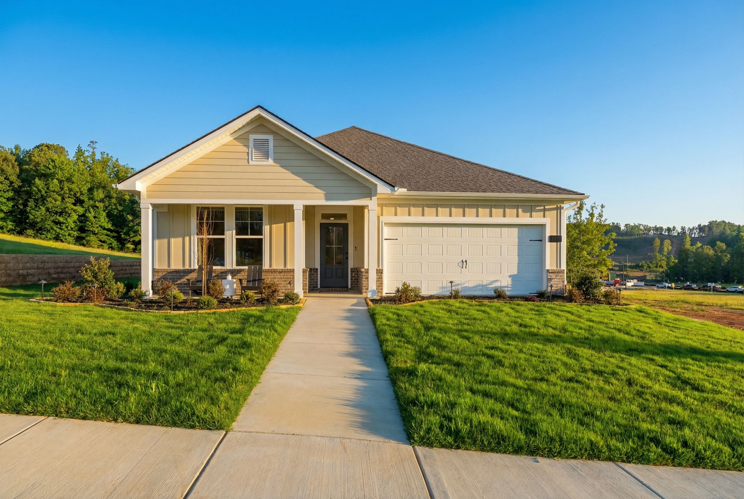 Modern single-story The Laurel K elevation featuring beige CementConcrete siding, gabled roof, two-car garage, and landscaped front yard in Cullman, AL