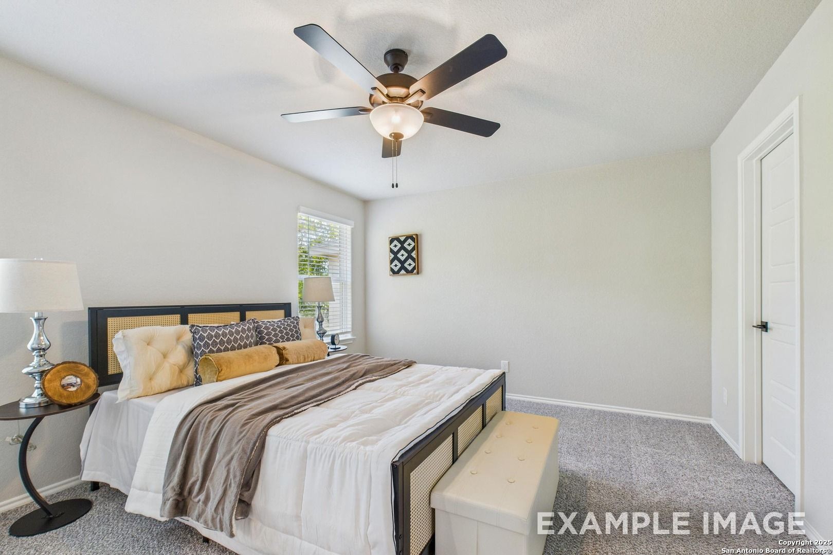 Cozy bedroom with plush king bed, ceiling fan, bedside lamps, and window in Davidson Homes The Charlotte A, San Antonio, Texas