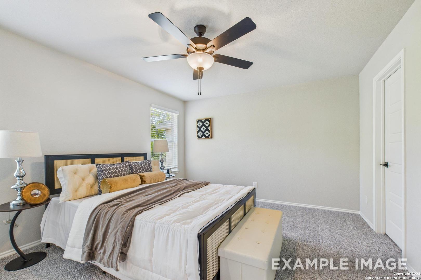 Serene master bedroom with king bed, decorative pillows, bedside lamps, and ceiling fan in Davidson Homes The Charlotte B, San Antonio