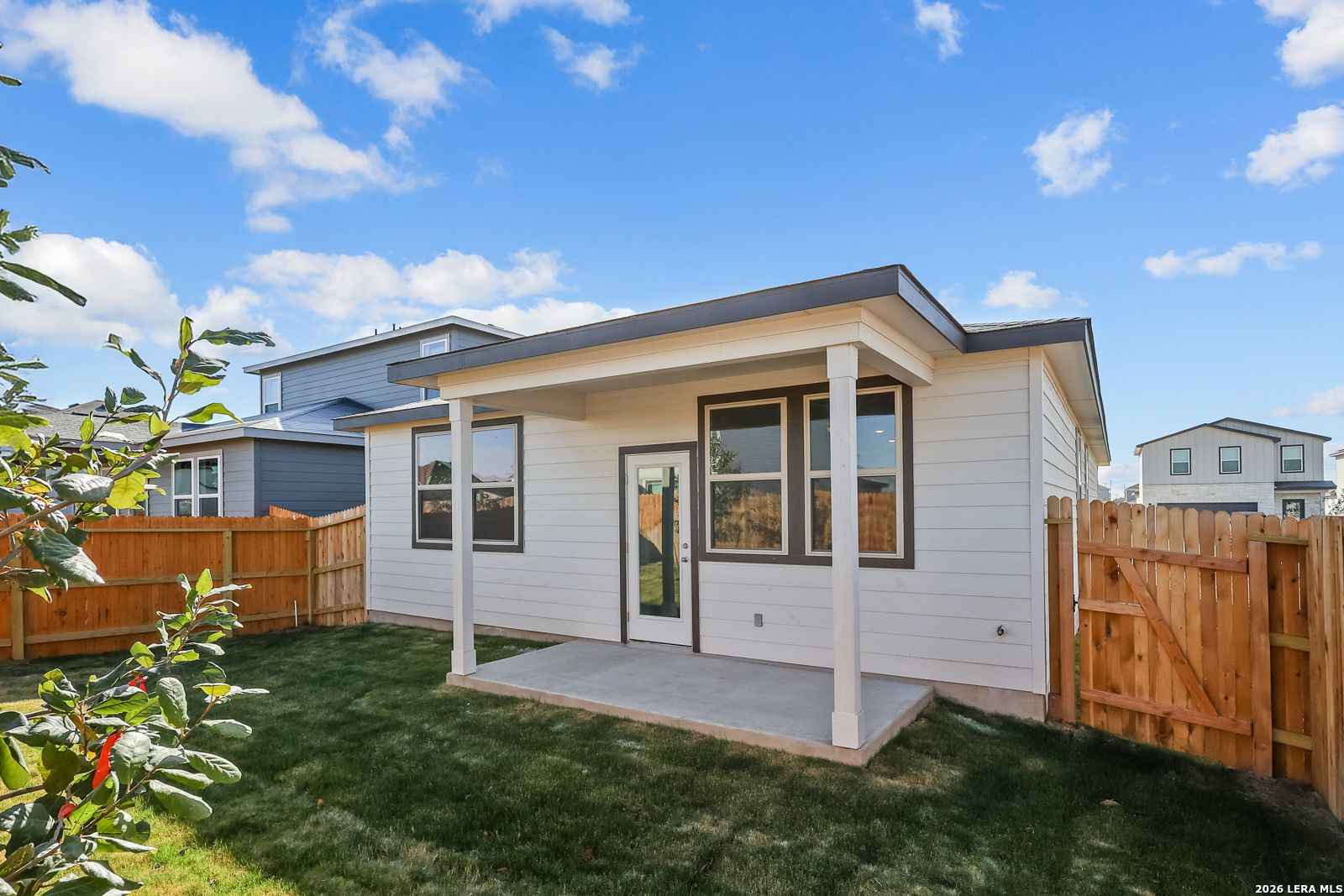 Modern 1-story Davidson Homes The Frio B exterior with covered porch, white siding, and fenced grassy yard in Applewhite Meadows, San Antonio