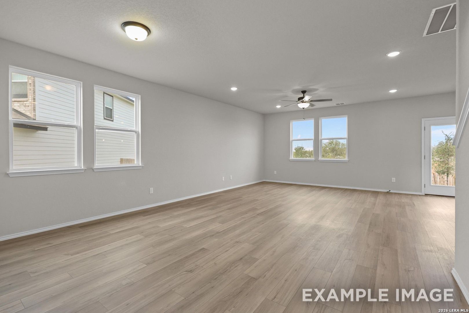 Bright open-concept living room with wood-look flooring and ceiling fan in Davidson Homes The Murray H, Converse, Texas