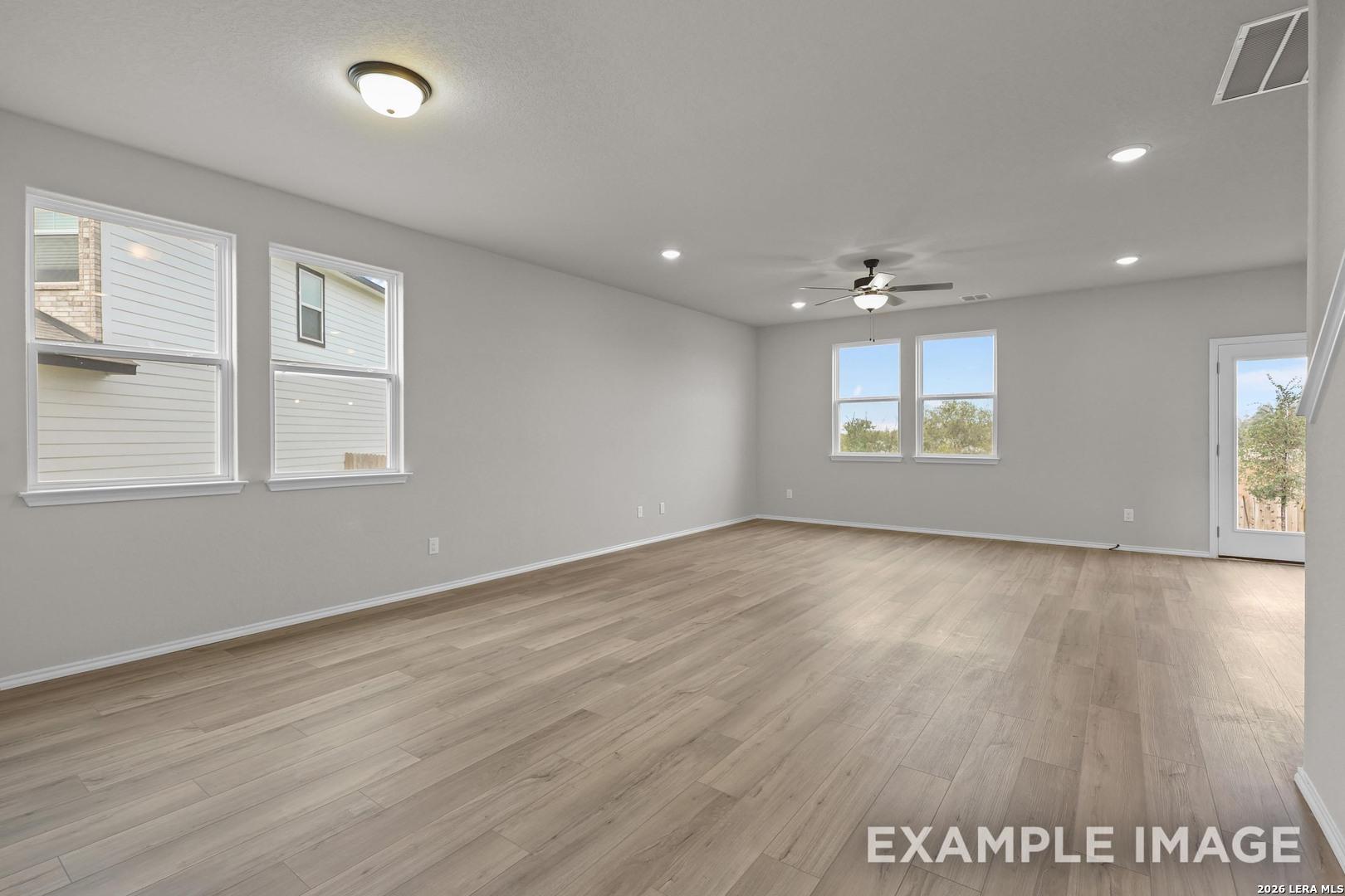 Bright open-concept living room with wood-look flooring and ceiling fan in Davidson Homes The Murray H, Converse, Texas
