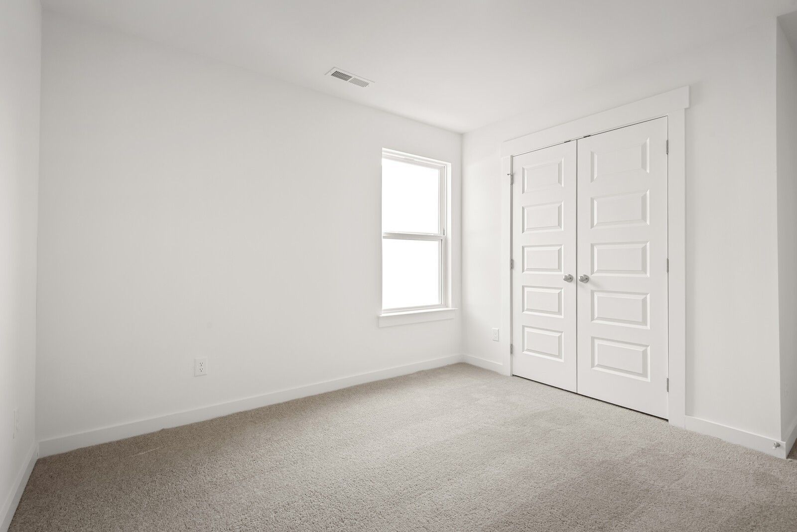 Bright secondary bedroom with double closet doors, large window, and neutral carpet in Davidson Homes The Logan C, Gallatin, TN