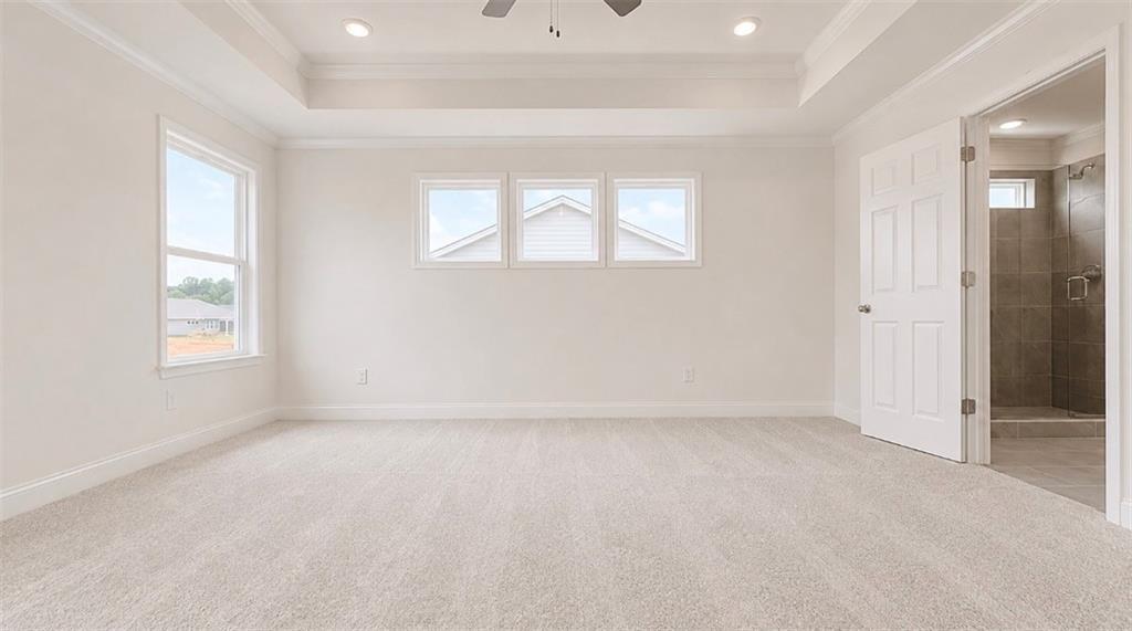 Bright primary bedroom with tray ceiling and en-suite bathroom in The Hickory C floor plan at Wehunt Meadows, Hoschton, GA.
