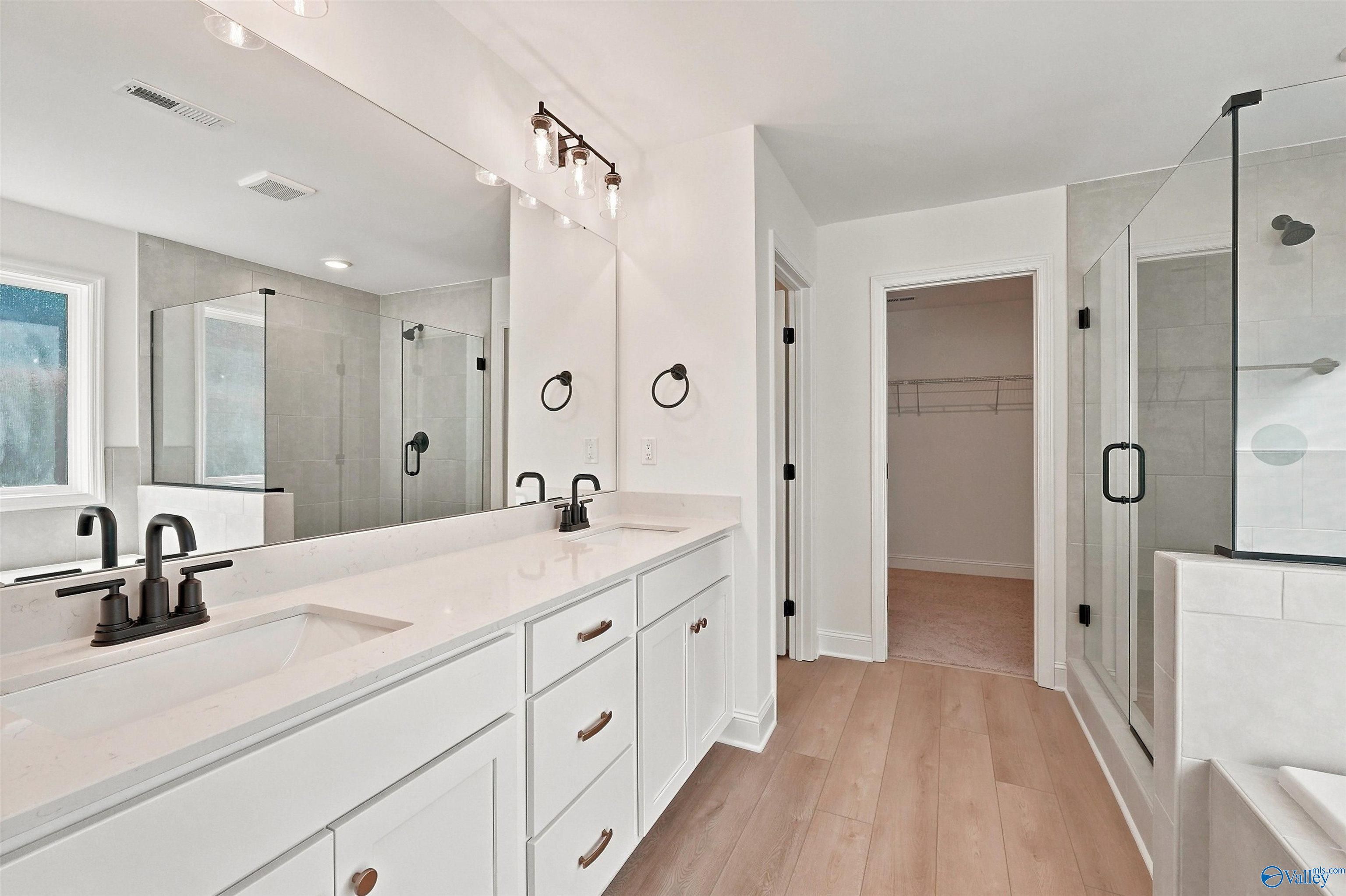 Modern master bathroom with double vanity, walk-in shower, and closet in The Chelsea C home at Creek Grove, New Market, AL.