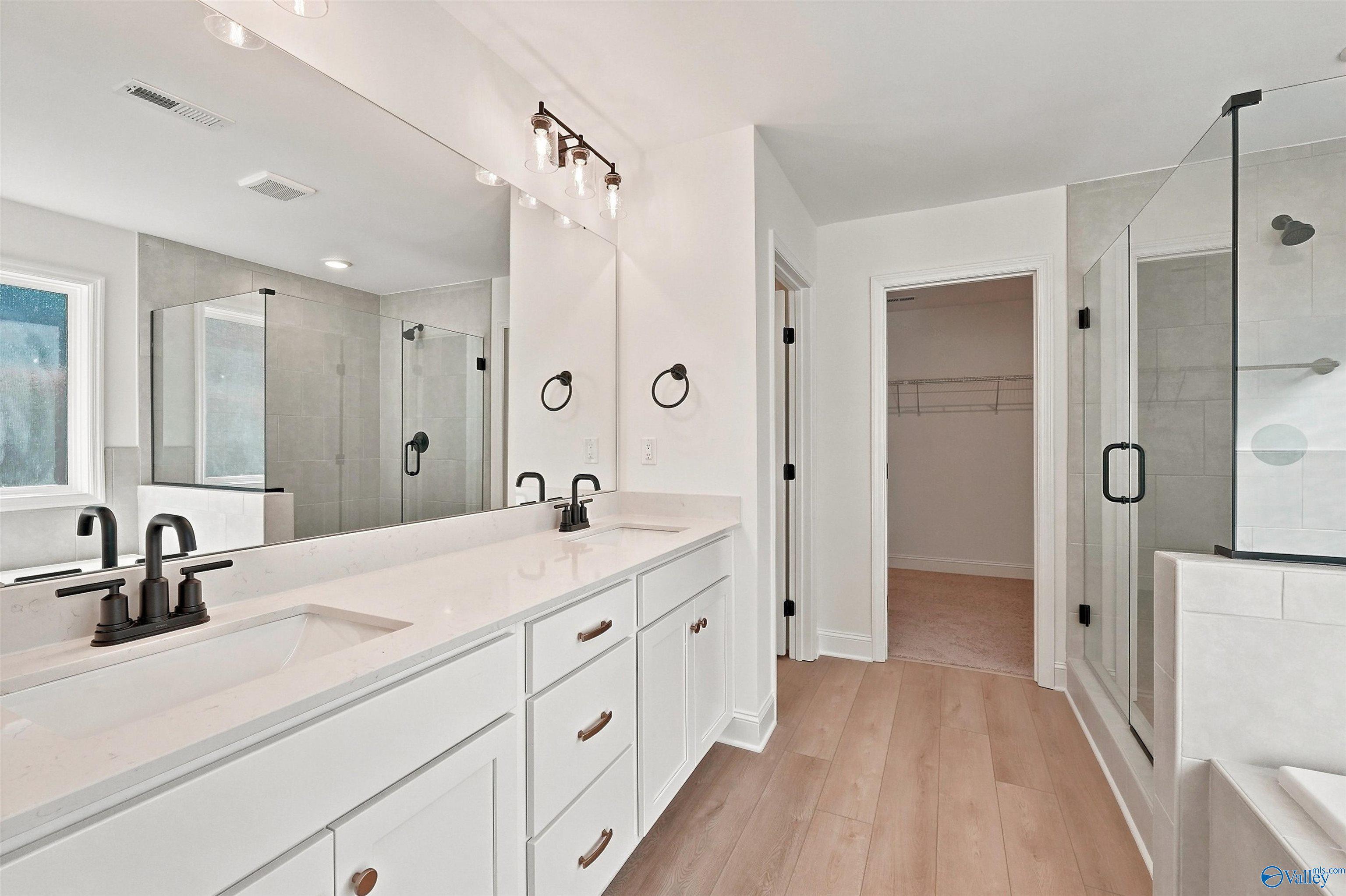 Modern master bathroom with double vanity, walk-in shower, and closet in The Chelsea C home at Creek Grove, New Market, AL.