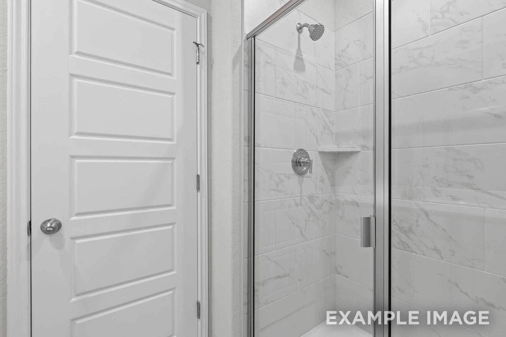 Modern walk-in shower with white marble-look tile in a Davidson Homes The Colorado G floor plan in Heartland, Texas.
