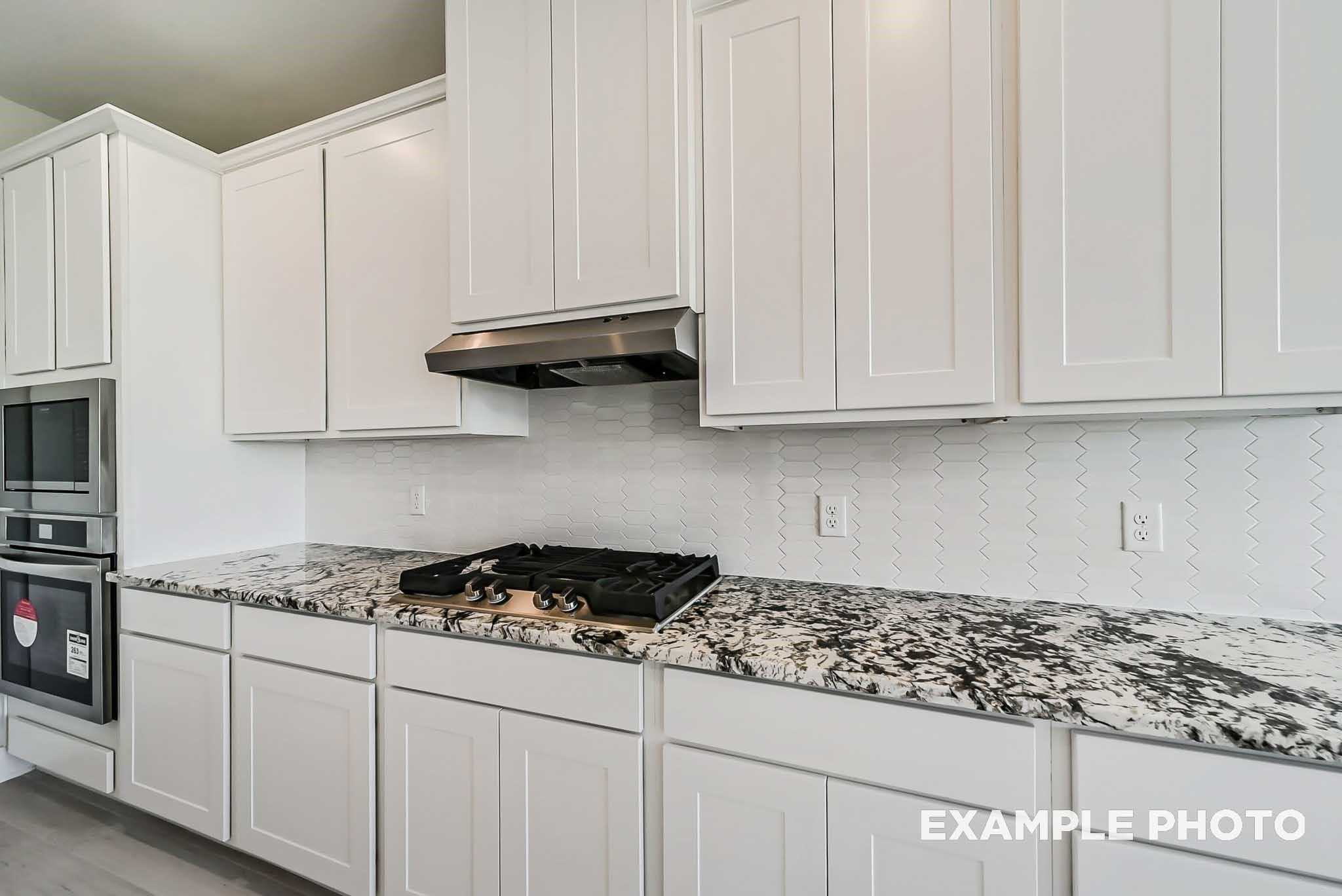 Modern white shaker kitchen with speckled granite counters, gas cooktop, stainless appliances in Davidson Homes The Philip C, Rosharon, Texas