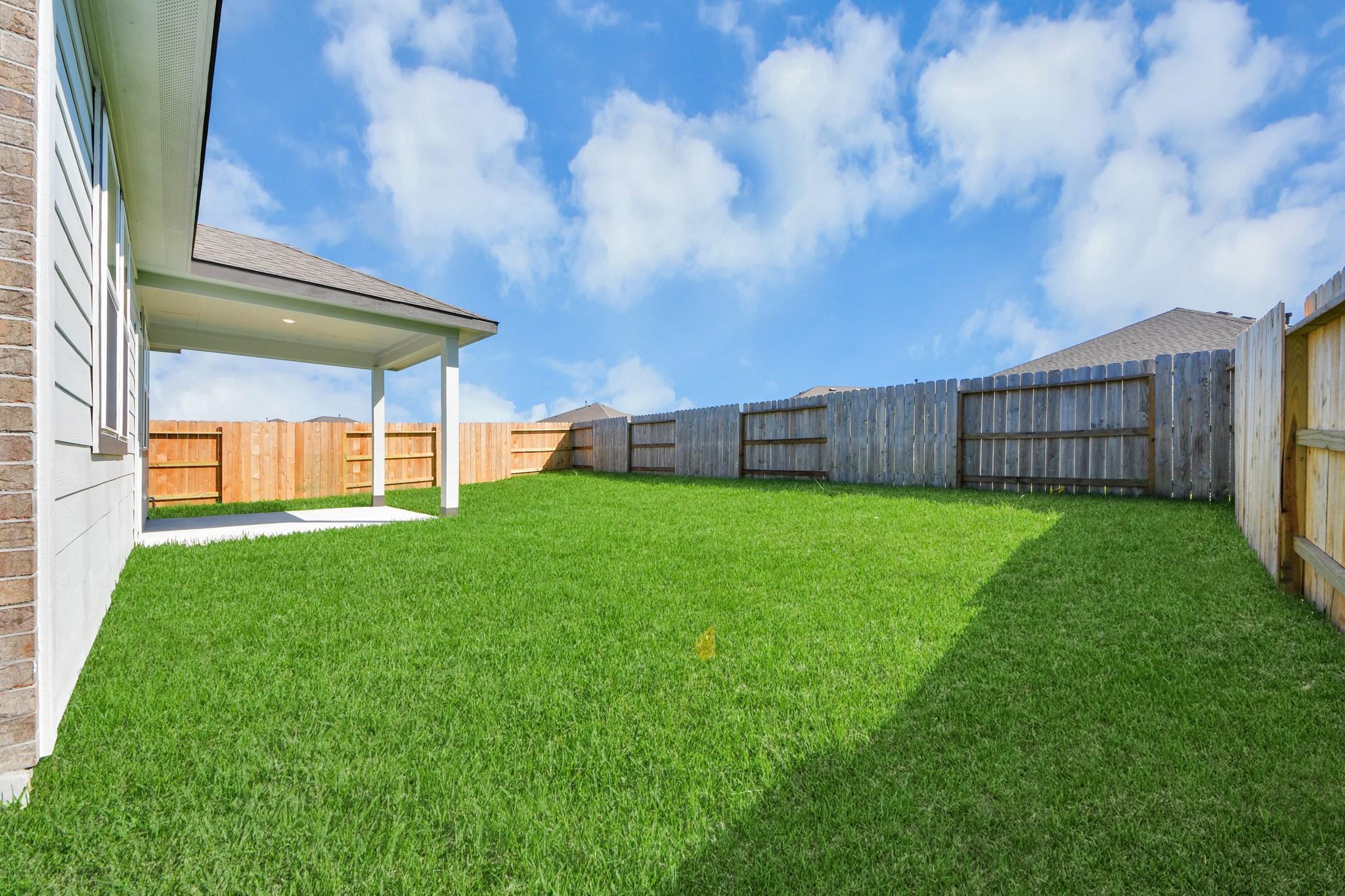 Covered back patio and private fenced backyard in the Colorado G floor plan at Emberly in Beasley, Texas.