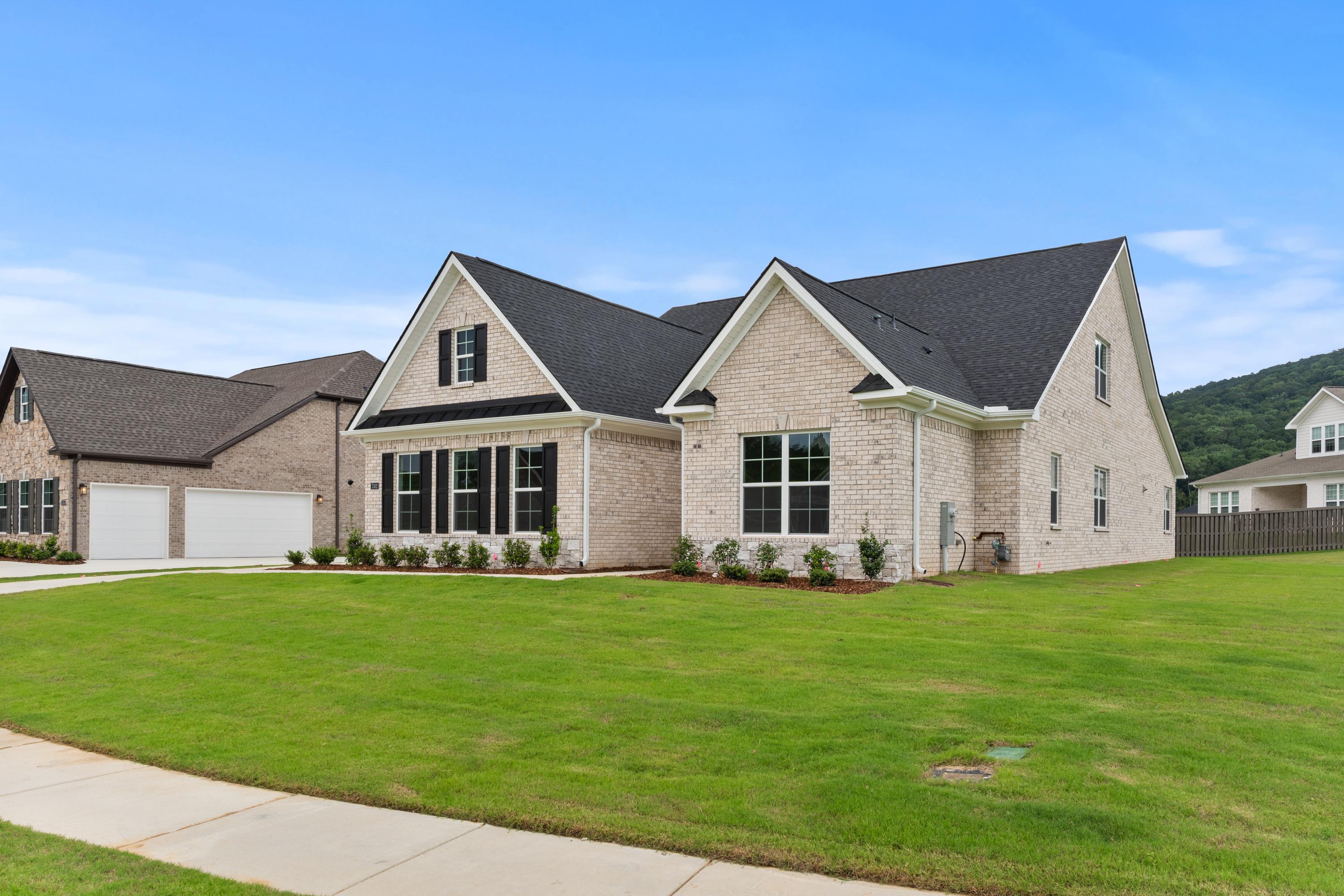 Two-story brick Oxford B home elevation with black shutters, 3-car garage, and lush green lawn in Owens Cross Roads