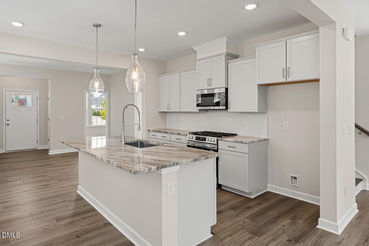 Modern kitchen with granite island and white cabinets in The Alexander C floor plan, Forestville Yard, Knightdale, NC.
