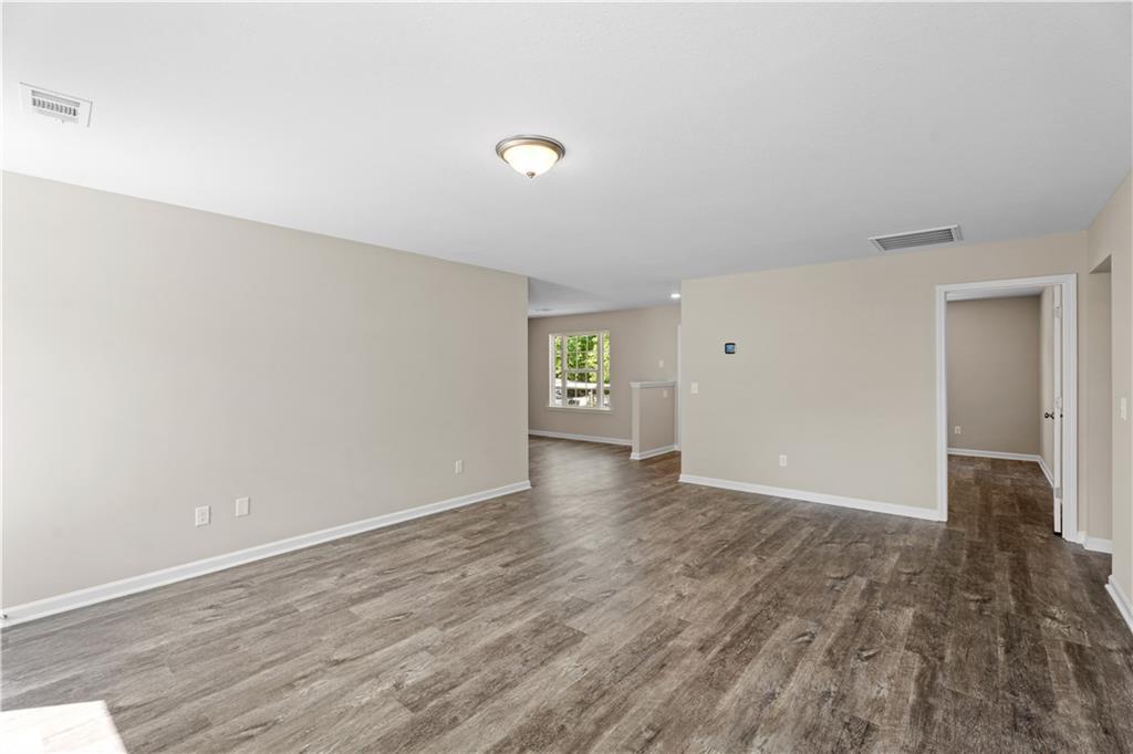 Open living space with light wood laminate floors, neutral beige walls, and doorways in 3-bedroom The Washington home, Phenix City, AL
