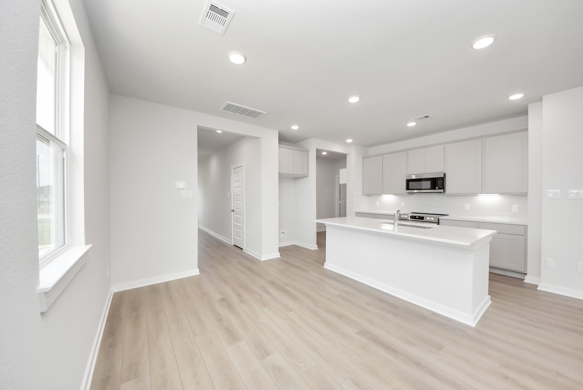 Modern kitchen with white island and gray cabinets in The Blanco F floor plan at Spring Branch Crossing, Conroe, Texas.